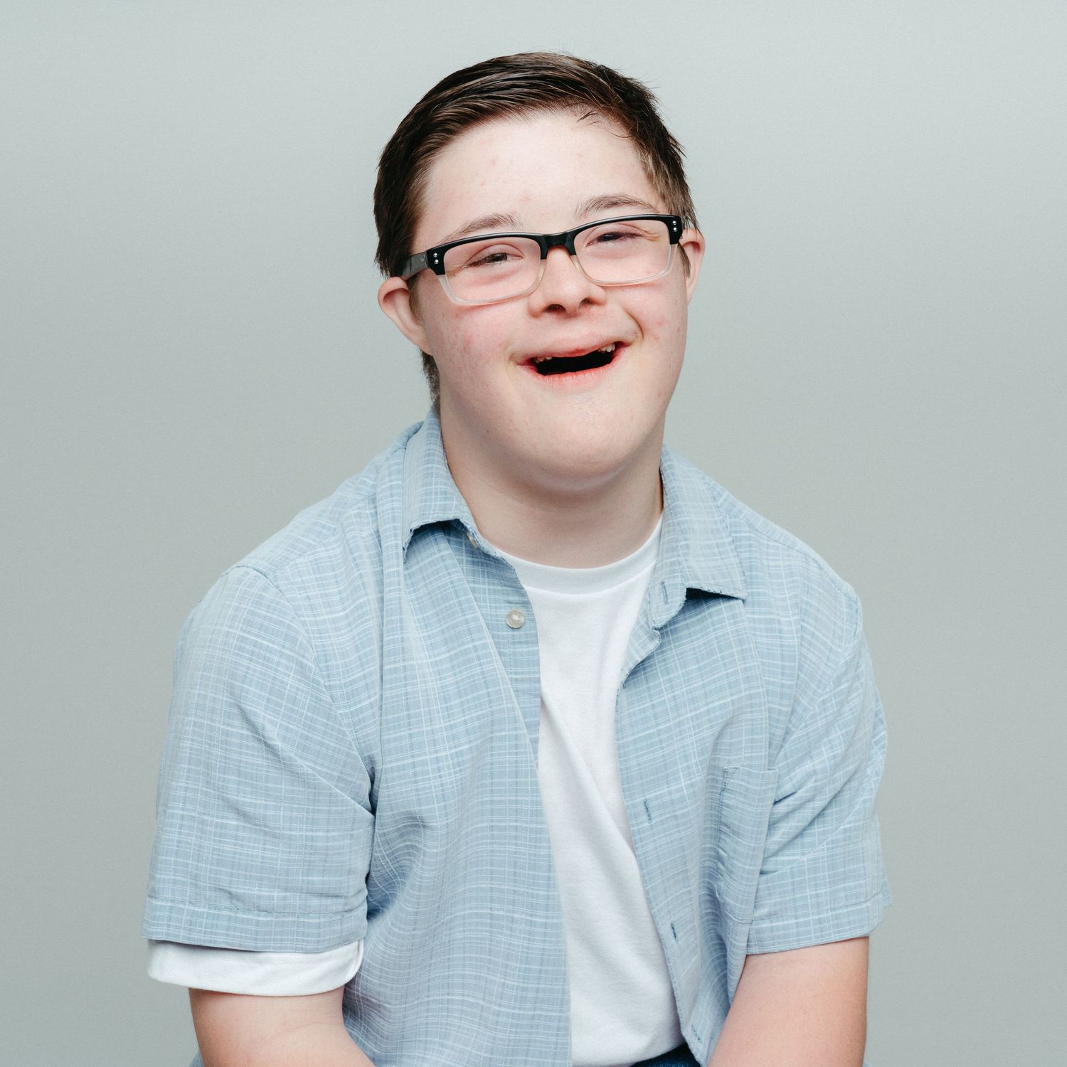 Portrait of a person wearing glasses and light blue shirt with joyful expression.
