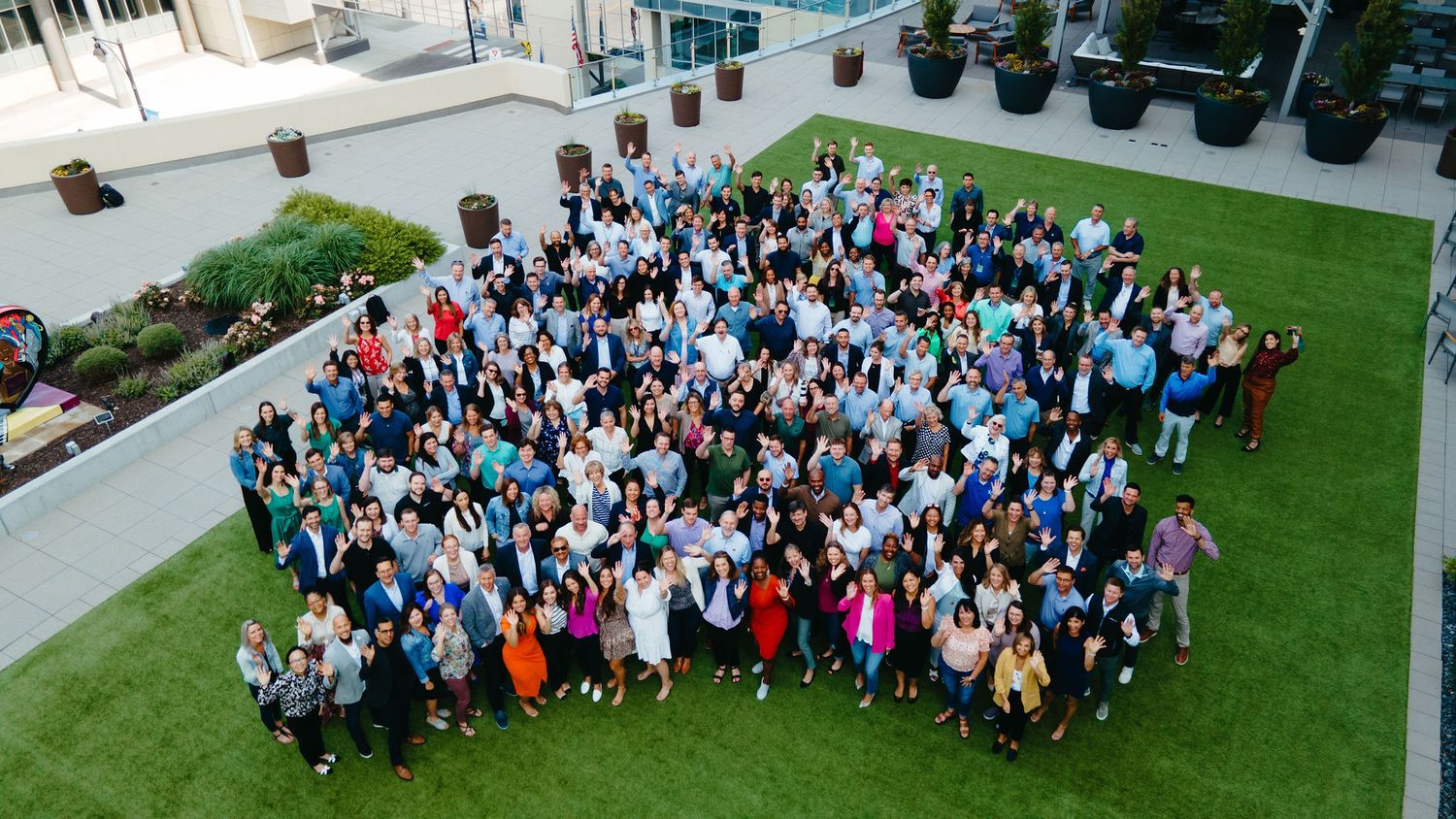 Large group photo of event attendees gathered outdoors on a sunny day.