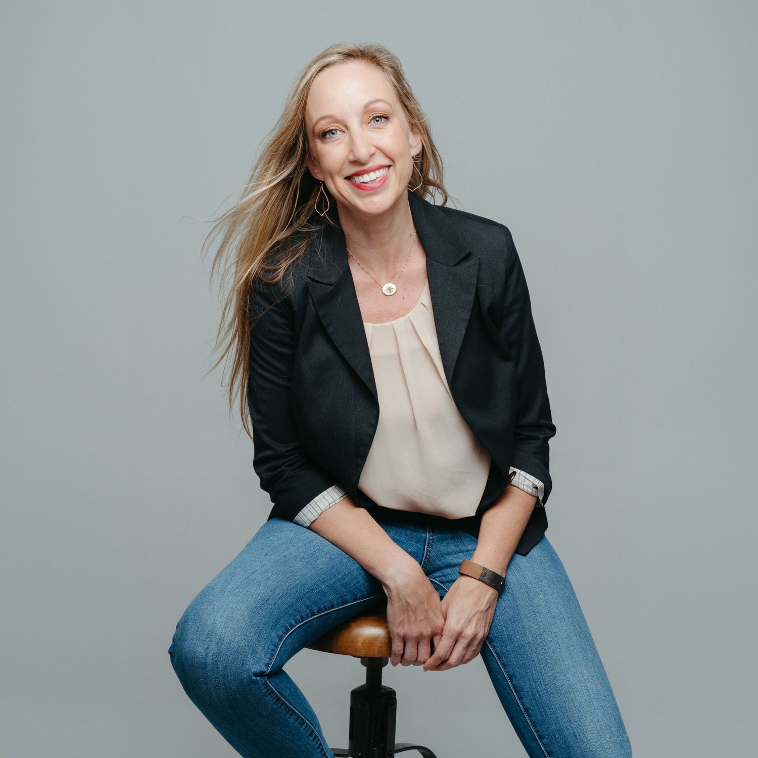 Business casual portraits of a person in a blazer and jeans on a gray background.