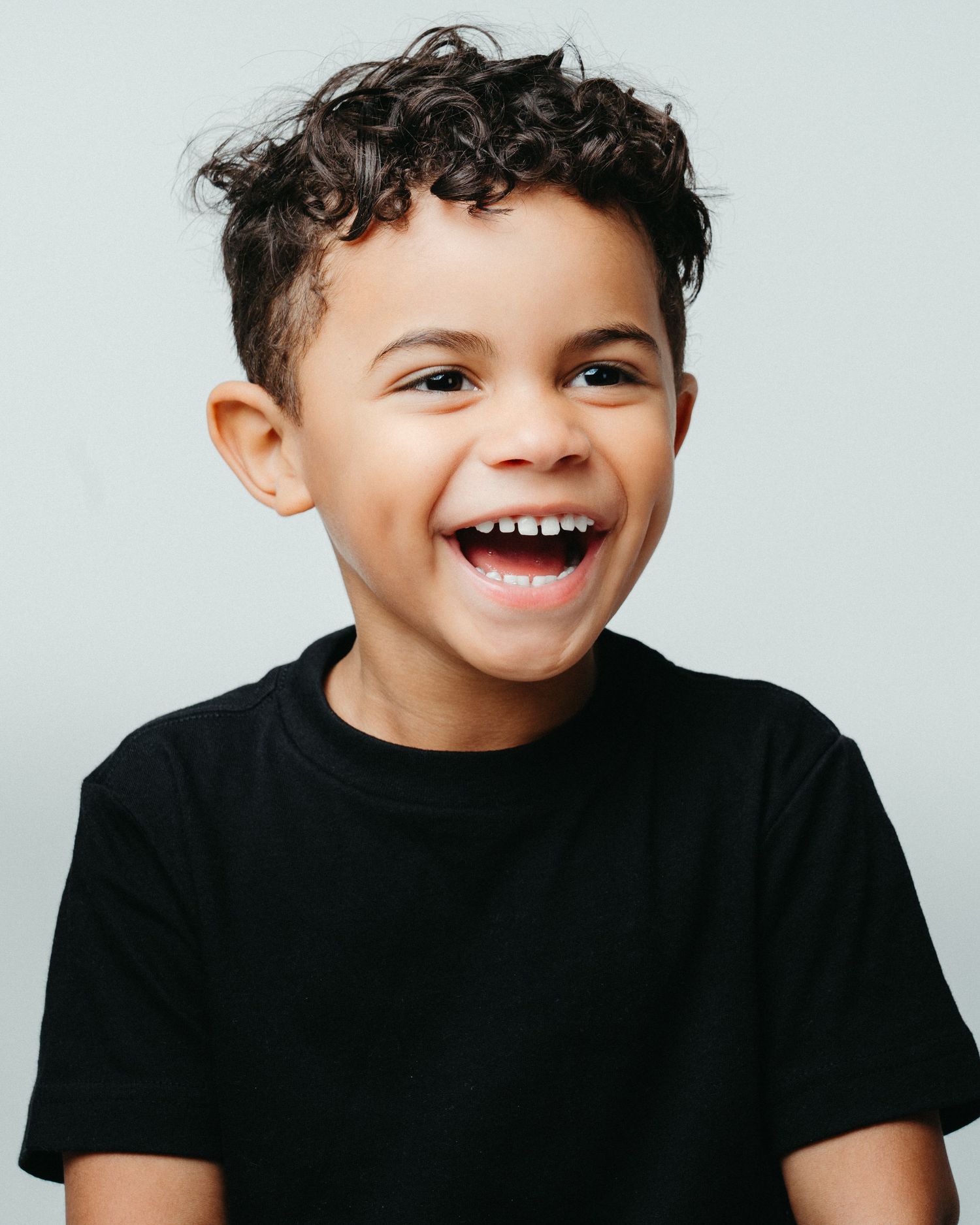 Series of candid expressions showing joyful laughter in black t-shirt against white background.