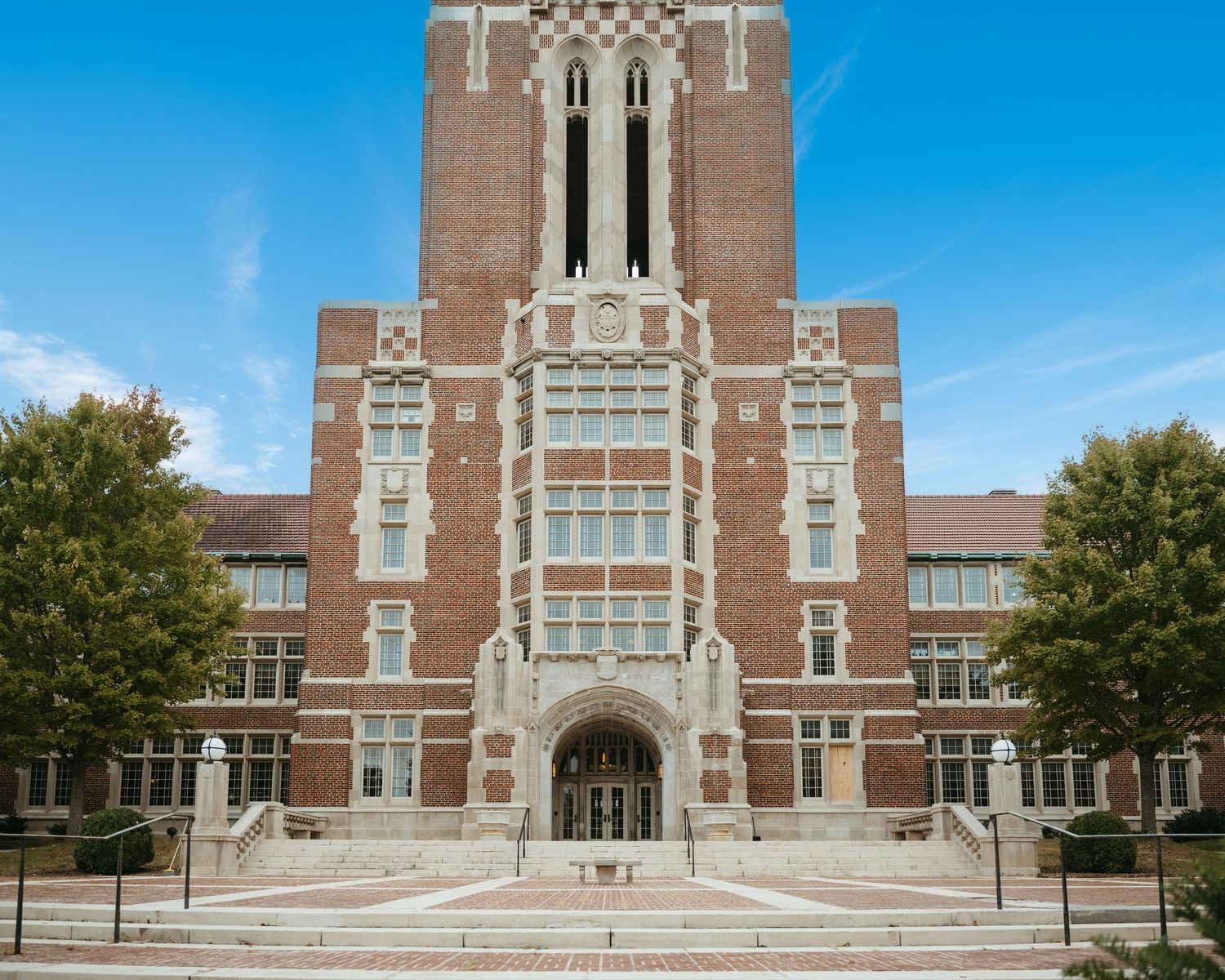 Wide view of collegiate Gothic style building entrance with stone steps and decorative trim.