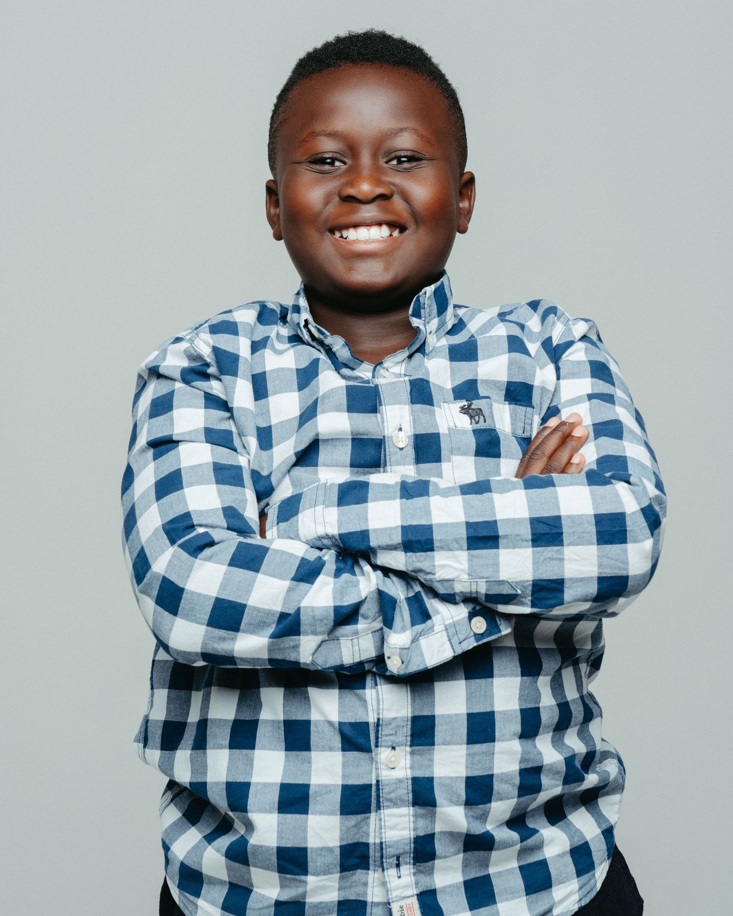 A series of five photos showing someone wearing a blue and white checkered shirt expressing different joyful emotions.