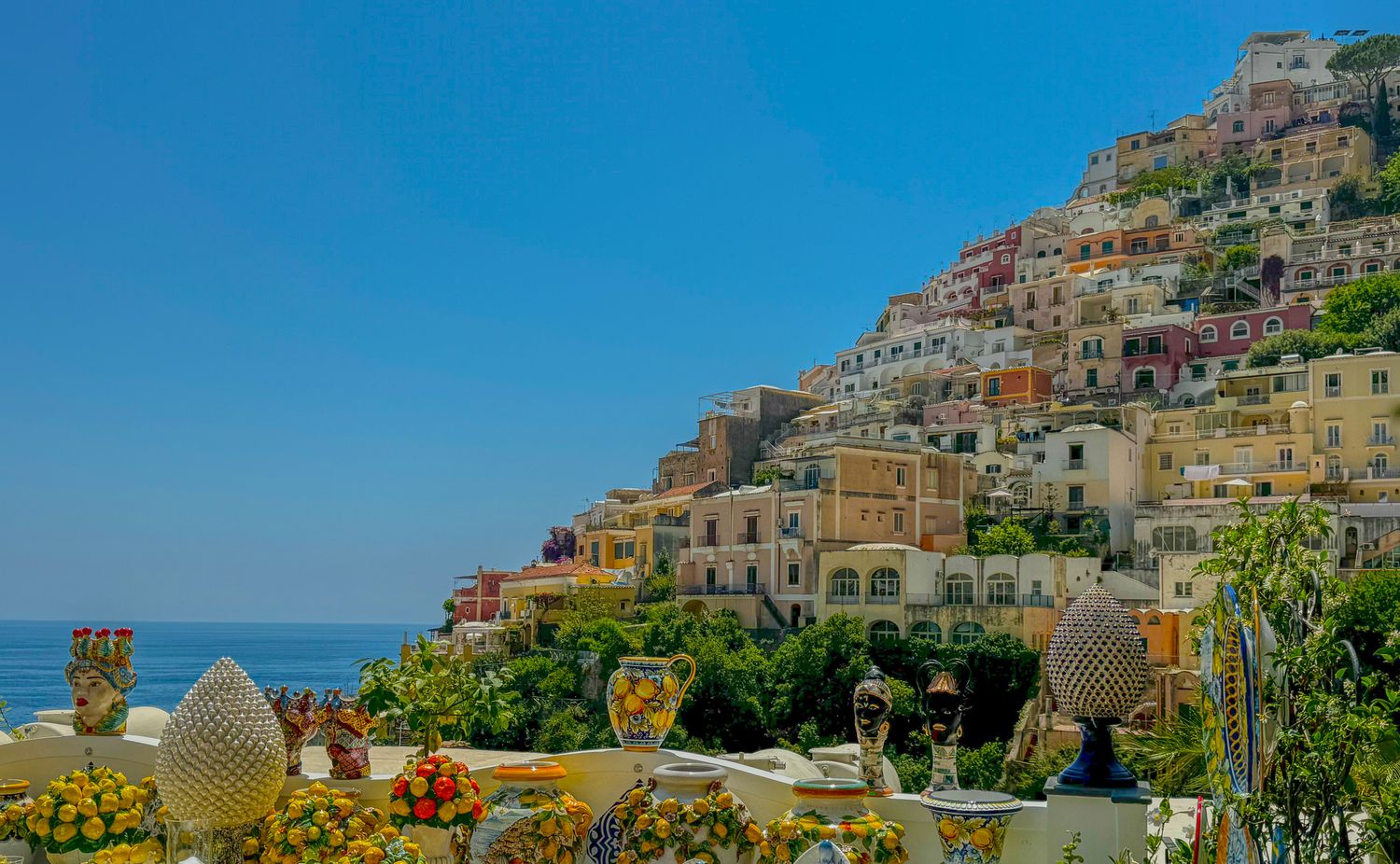 Colorful cliffside village of Positano with cascading buildings overlooking the blue Amalfi Coast sea.