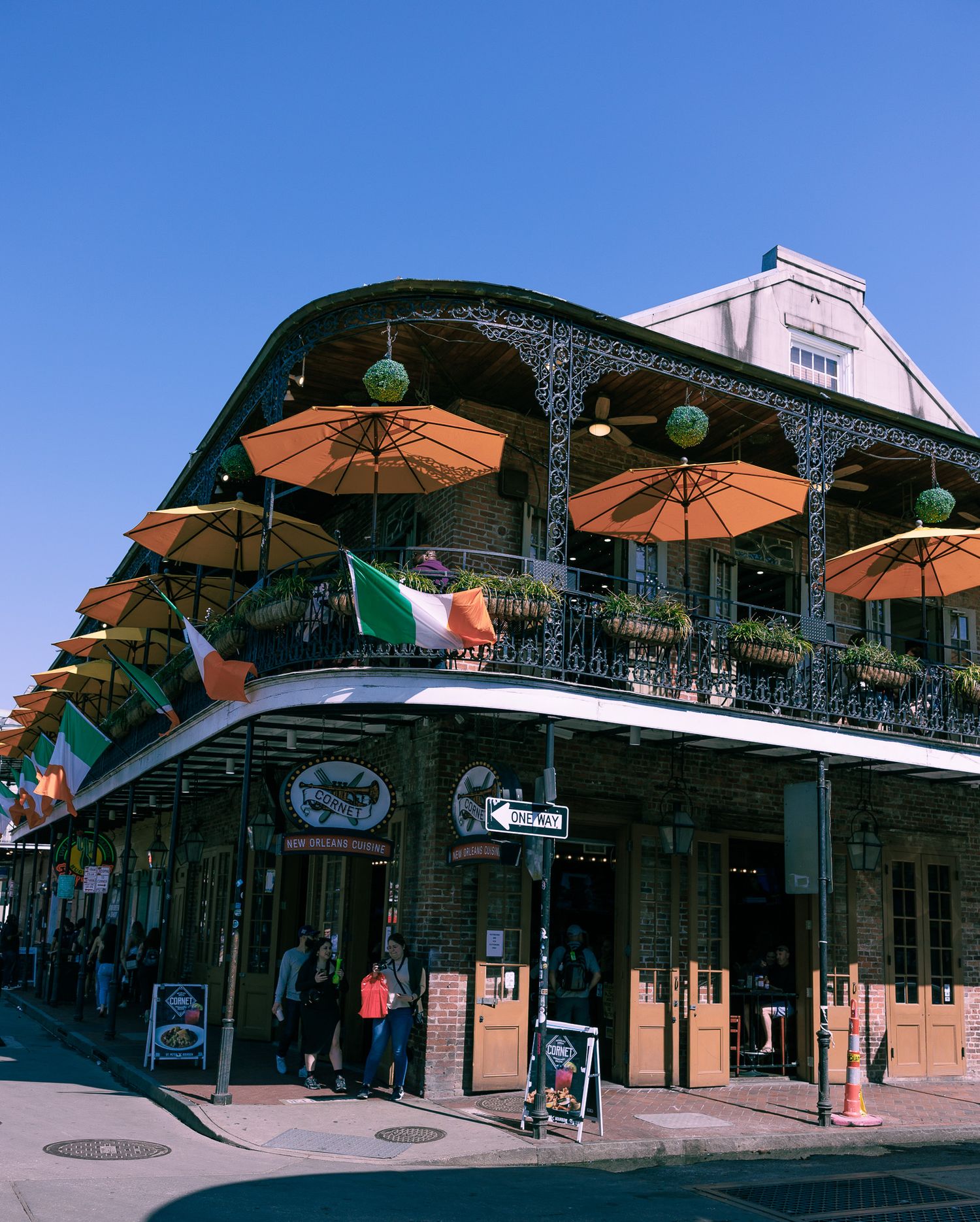 Iconic French Quarter building in New Orleans with ornate ironwork balconies and orange patio umbrellas.