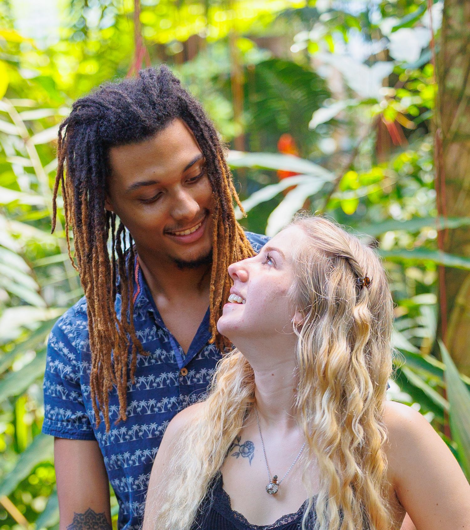 Happy couple smiling at each other in a lush tropical garden setting.