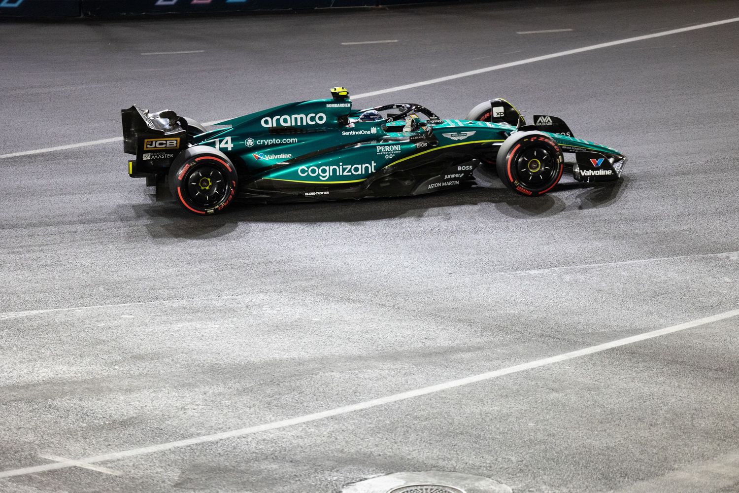 Aston Martin Aramco F1 car number 14 racing on wet Las Vegas Grand Prix circuit at night.