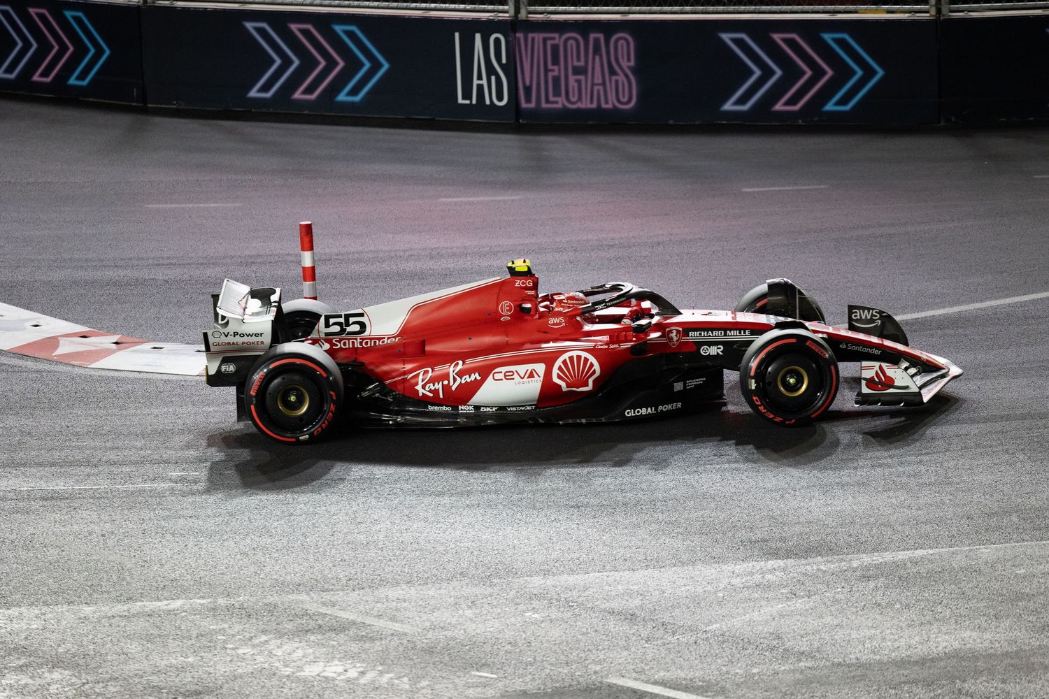 Ferrari F1 car number 55 racing on wet Las Vegas street circuit at night.