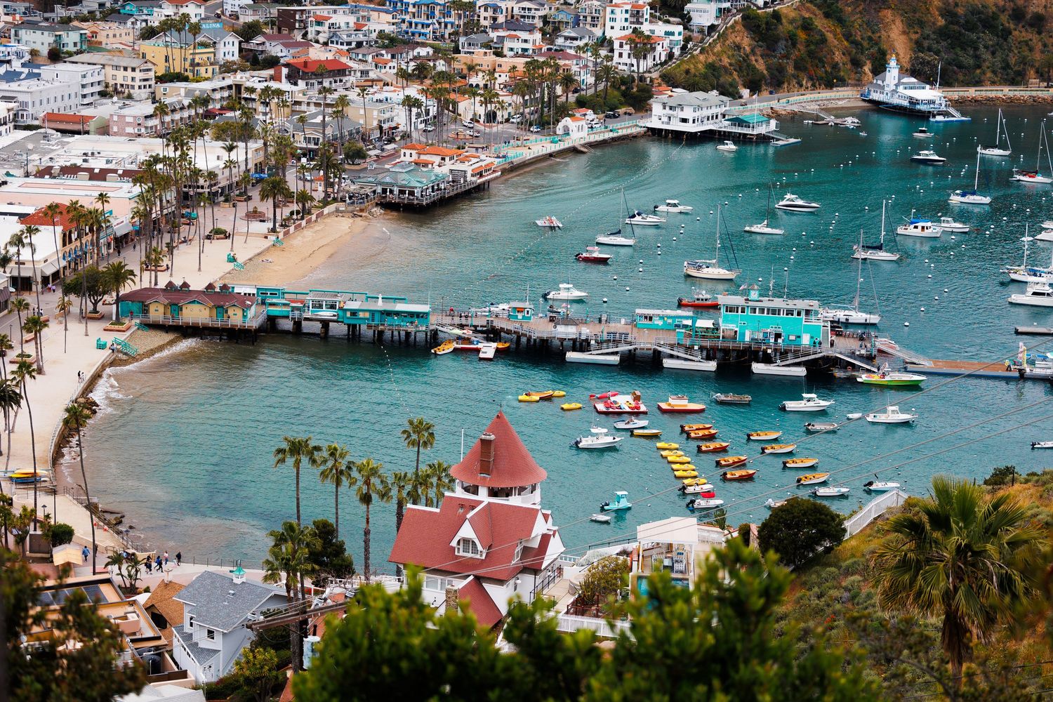 Aerial view of Avalon Harbor on Catalina Island with boats, pier, and colorful waterfront buildings.