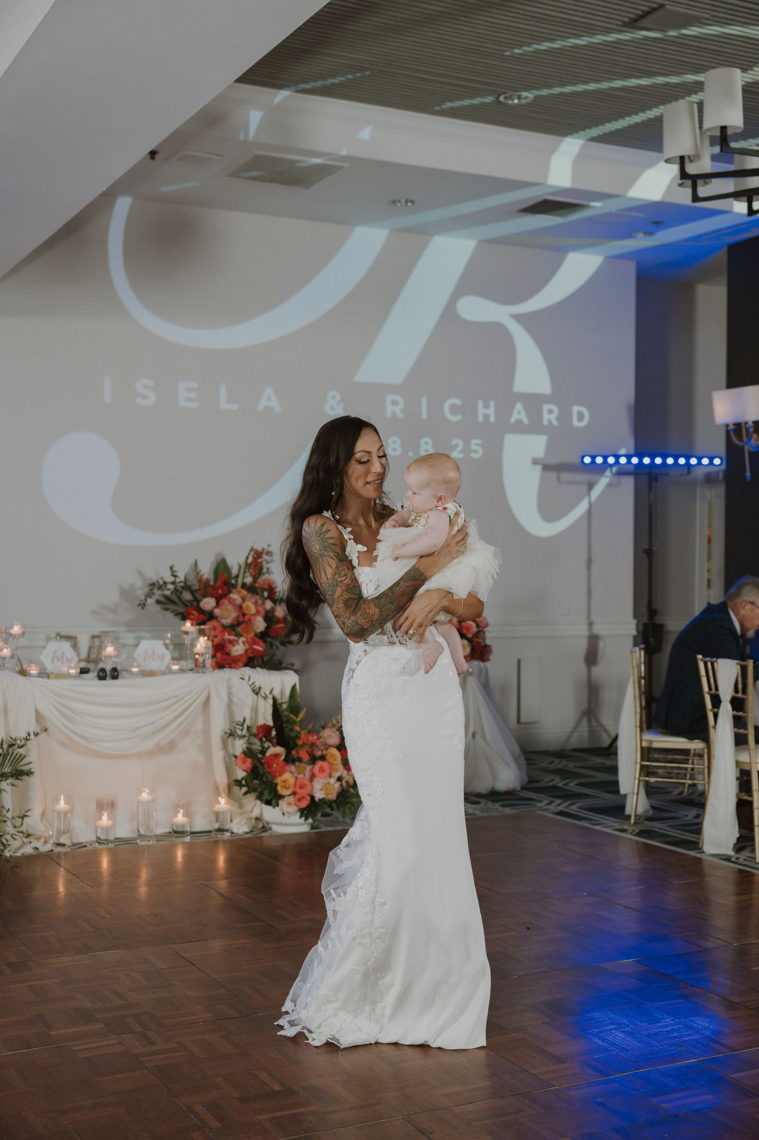 Wedding celebration on dance floor with romantic lighting and projected monogram.
