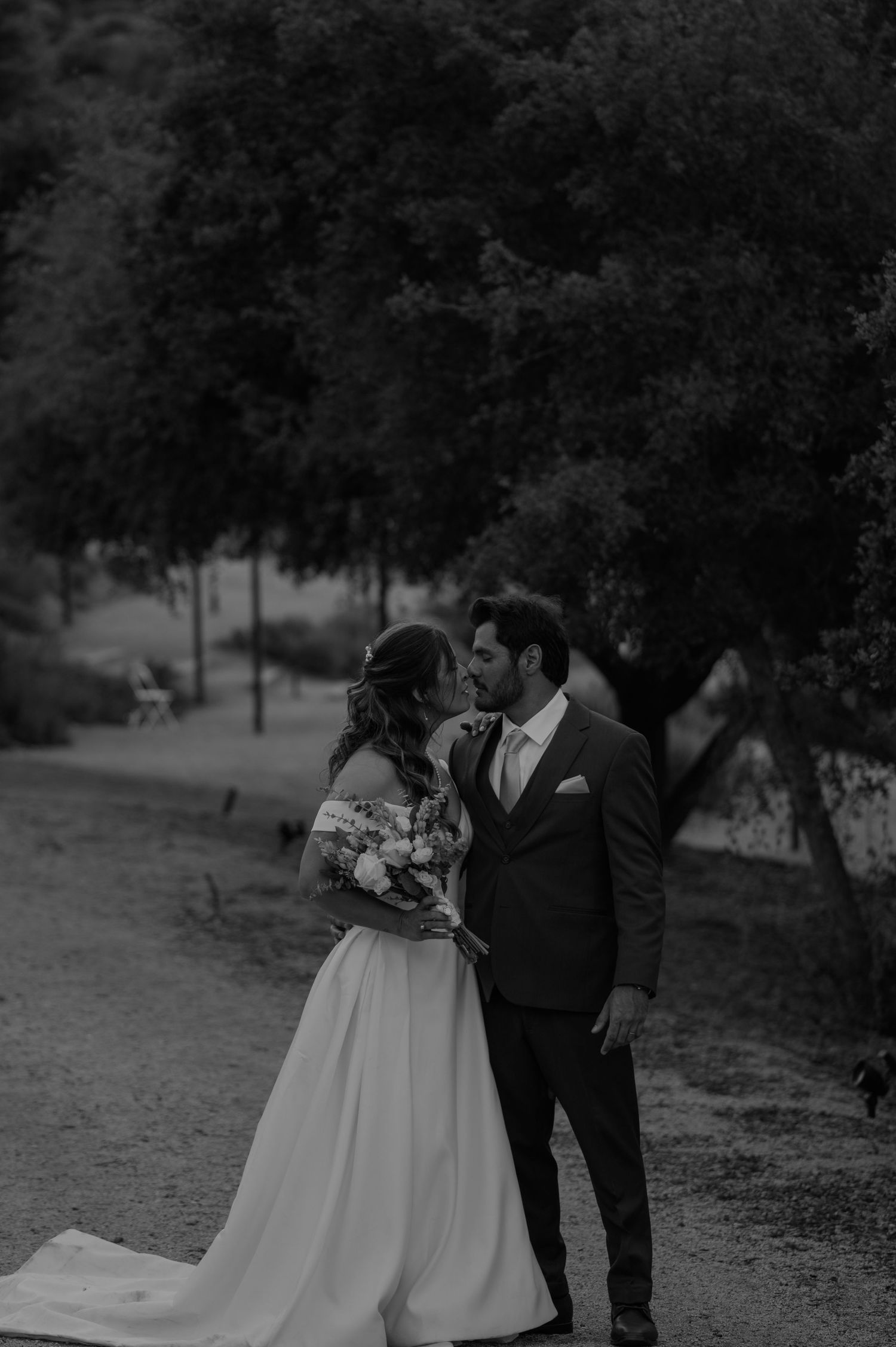 Elegant wedding couple photographed in a romantic outdoor setting at dusk.