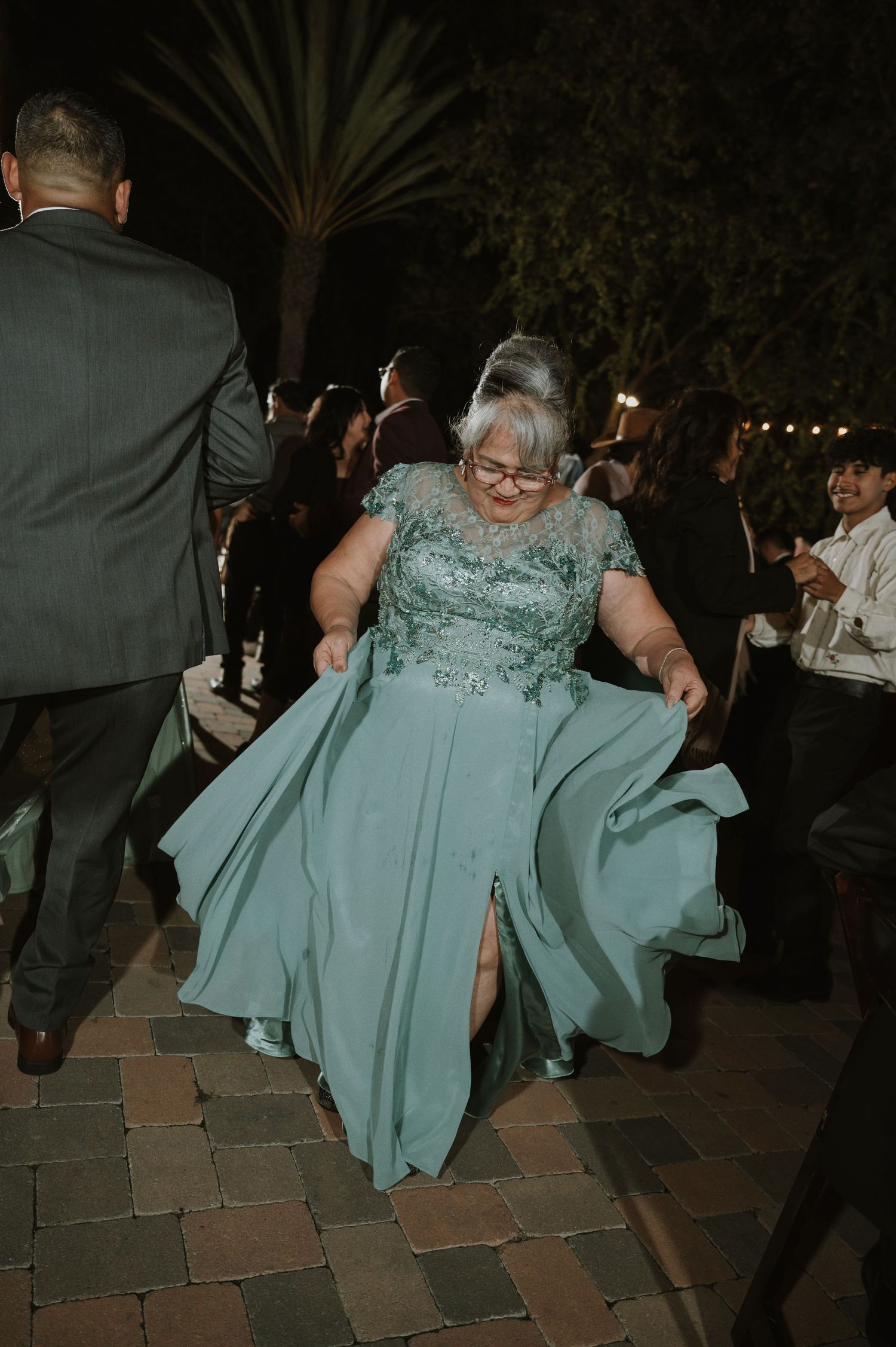 Guest in a mint green dress dancing at an outdoor wedding reception.