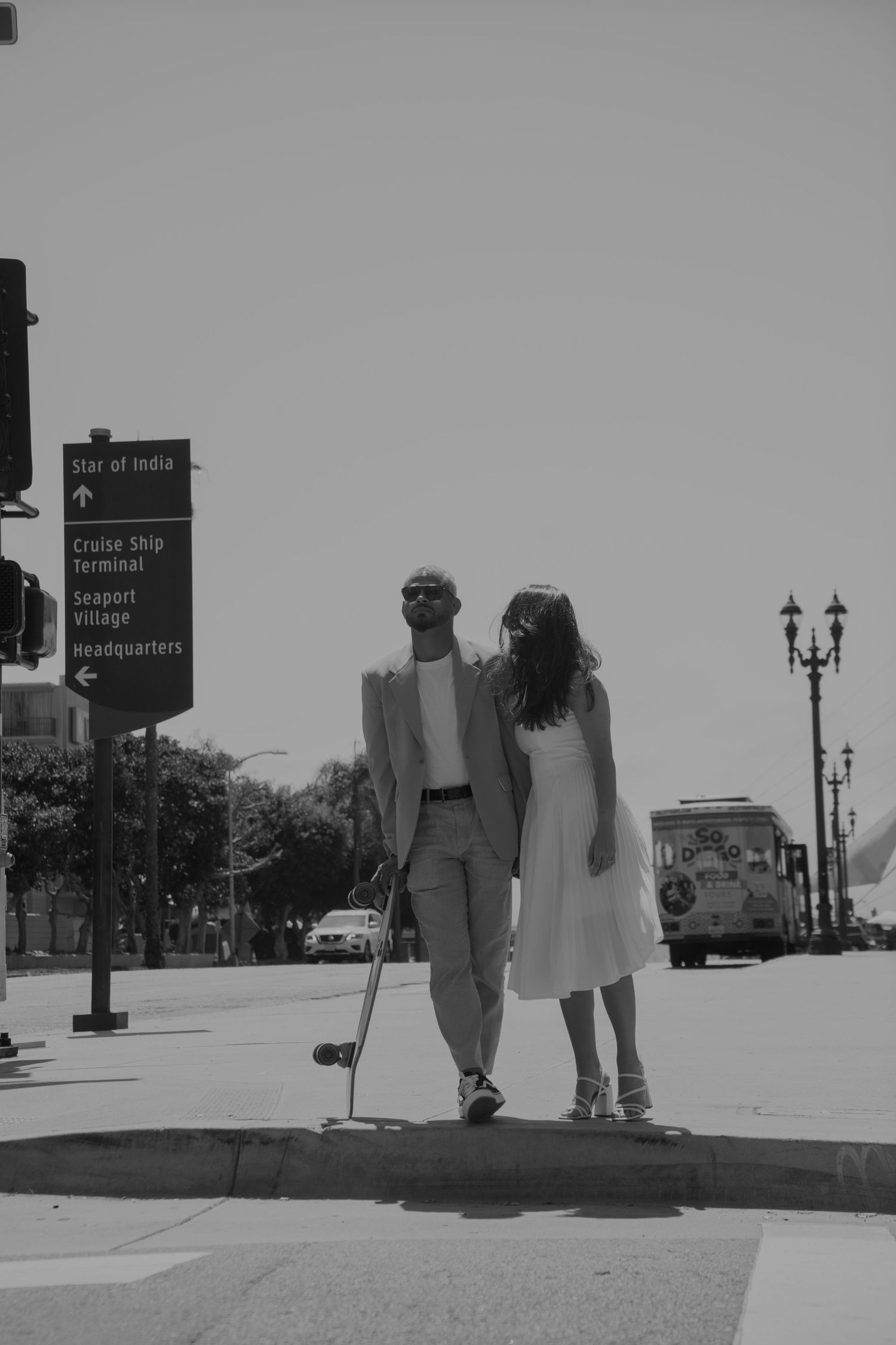 Couple walking together on a city street with directional signs visible.
