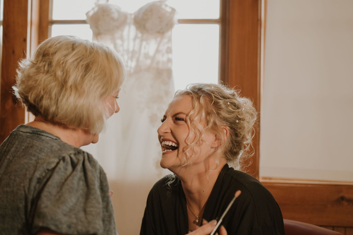 Warm-toned candid moments captured in window light during wedding preparations.