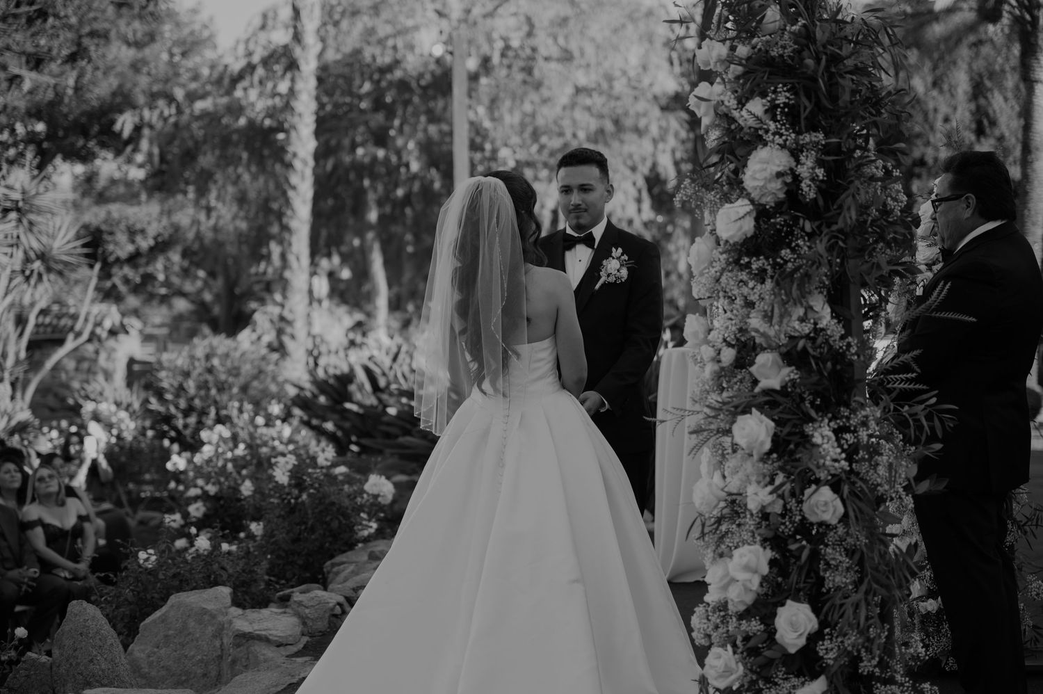 Black and white wedding ceremony photos showing guests seated in an outdoor garden setting.