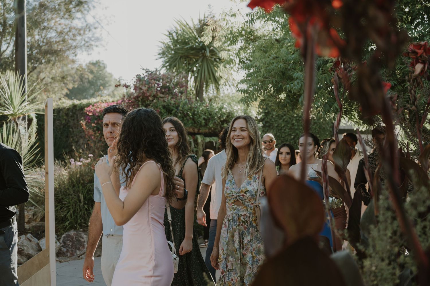 Guests mingling outdoors at a garden wedding reception surrounded by lush tropical greenery.