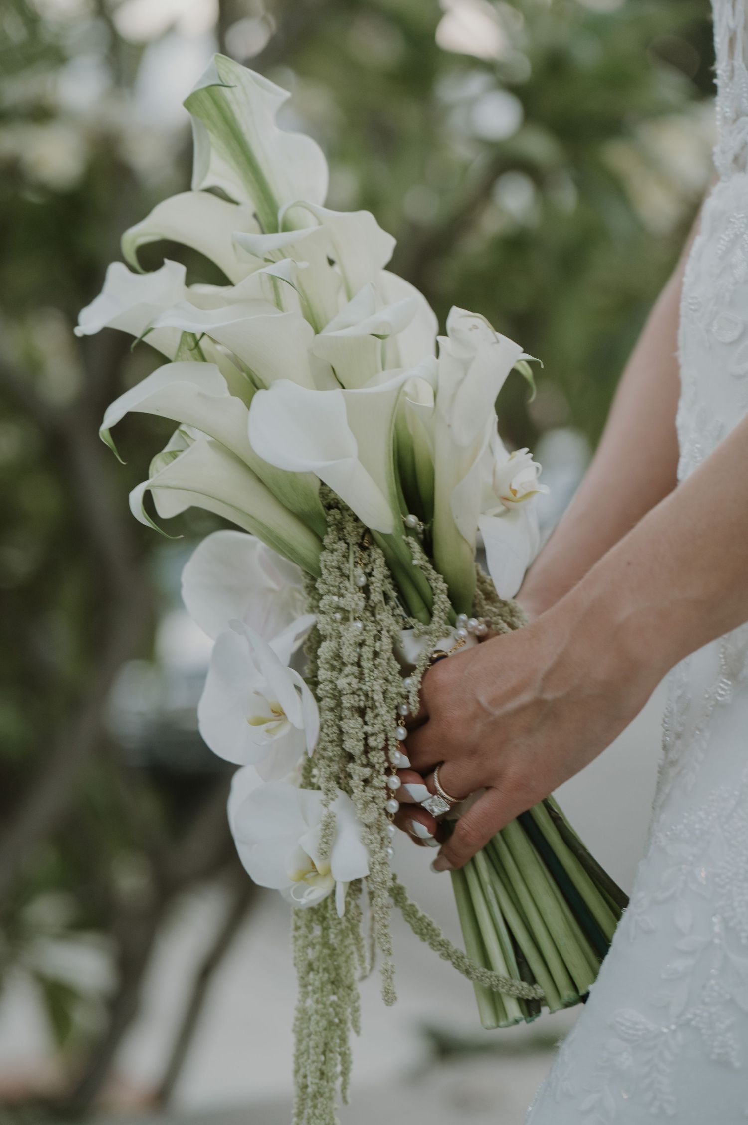 Close-up of a bridal bouquet featuring white calla lilies and orchids with cascading greenery.