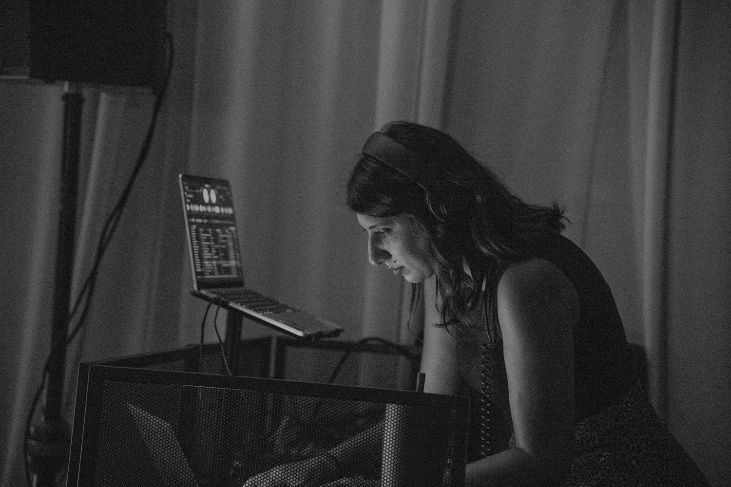 Black and white photo of female DJ working at sound equipment during wedding reception.