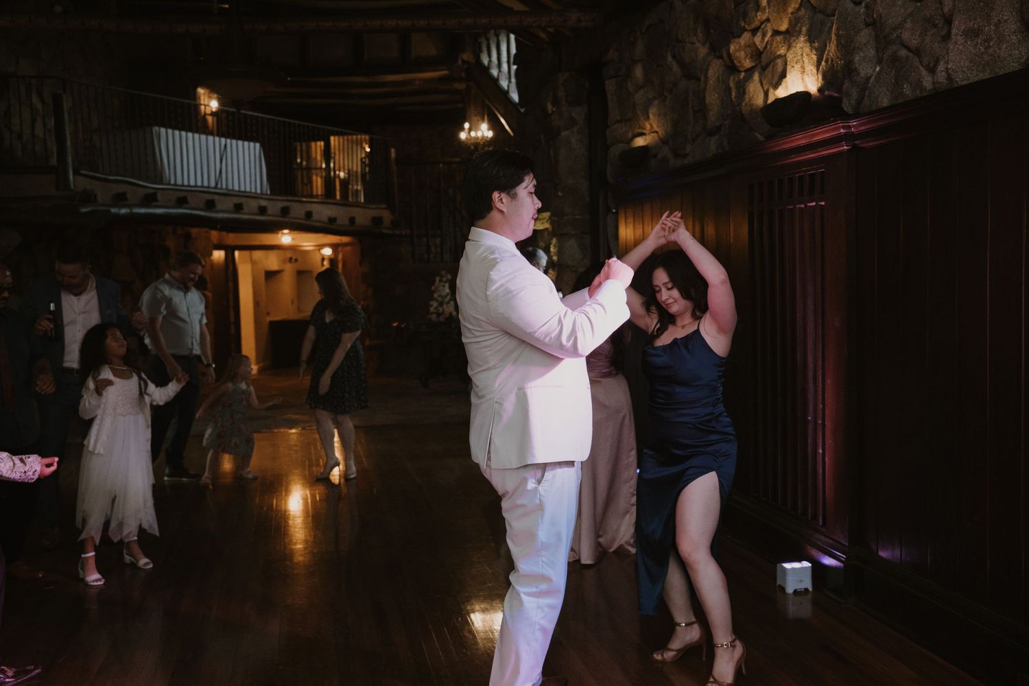Couple dancing together in an elegant dimly lit wedding reception venue.