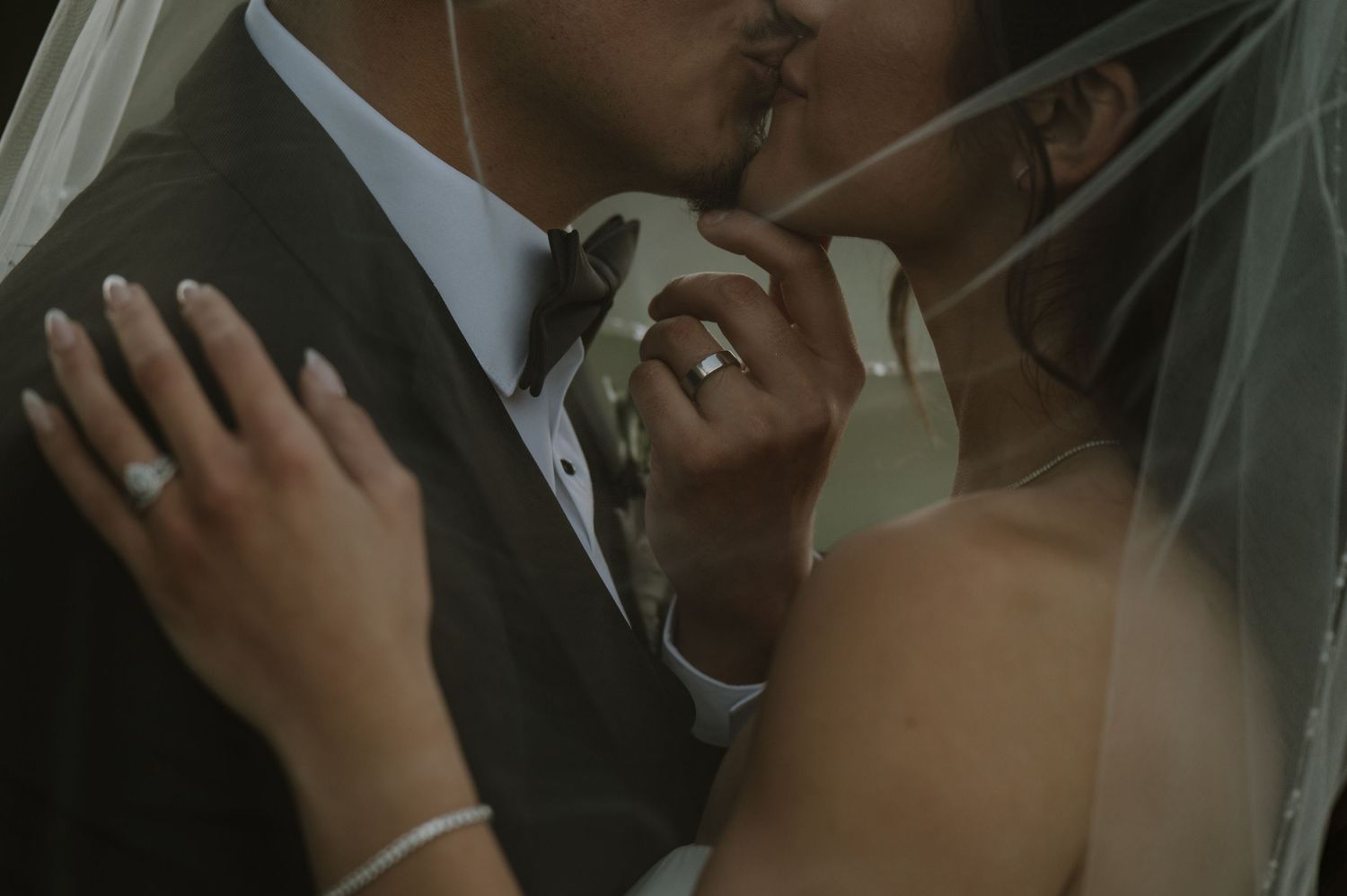 Intimate close-up of tender moment between newlyweds through delicate bridal veil.