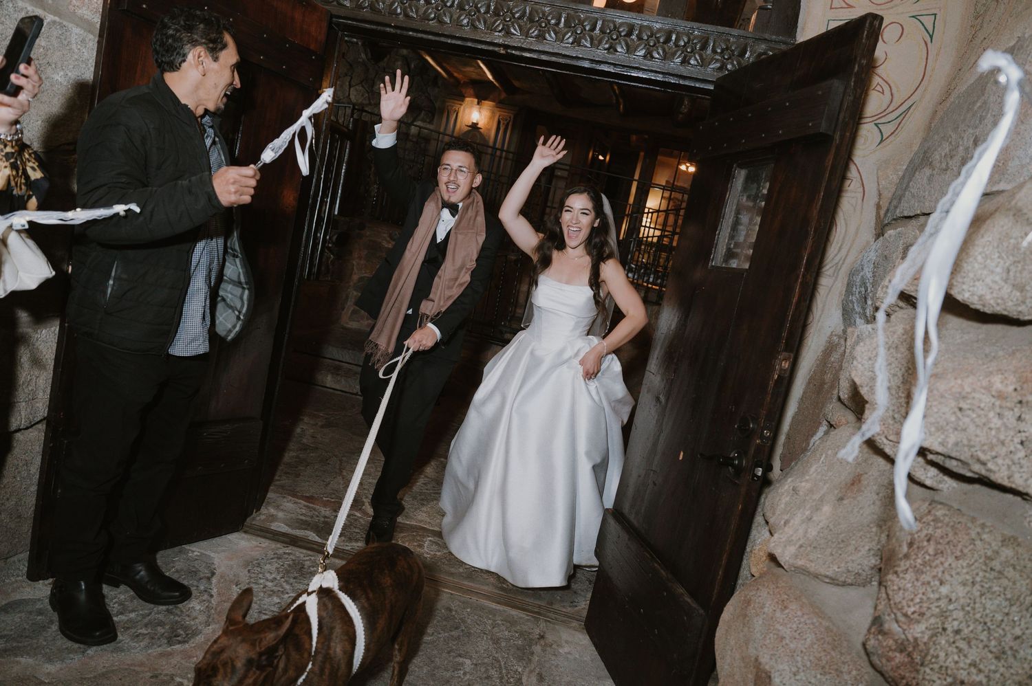 Wedding reception dance party in a dimly lit stone-walled venue.