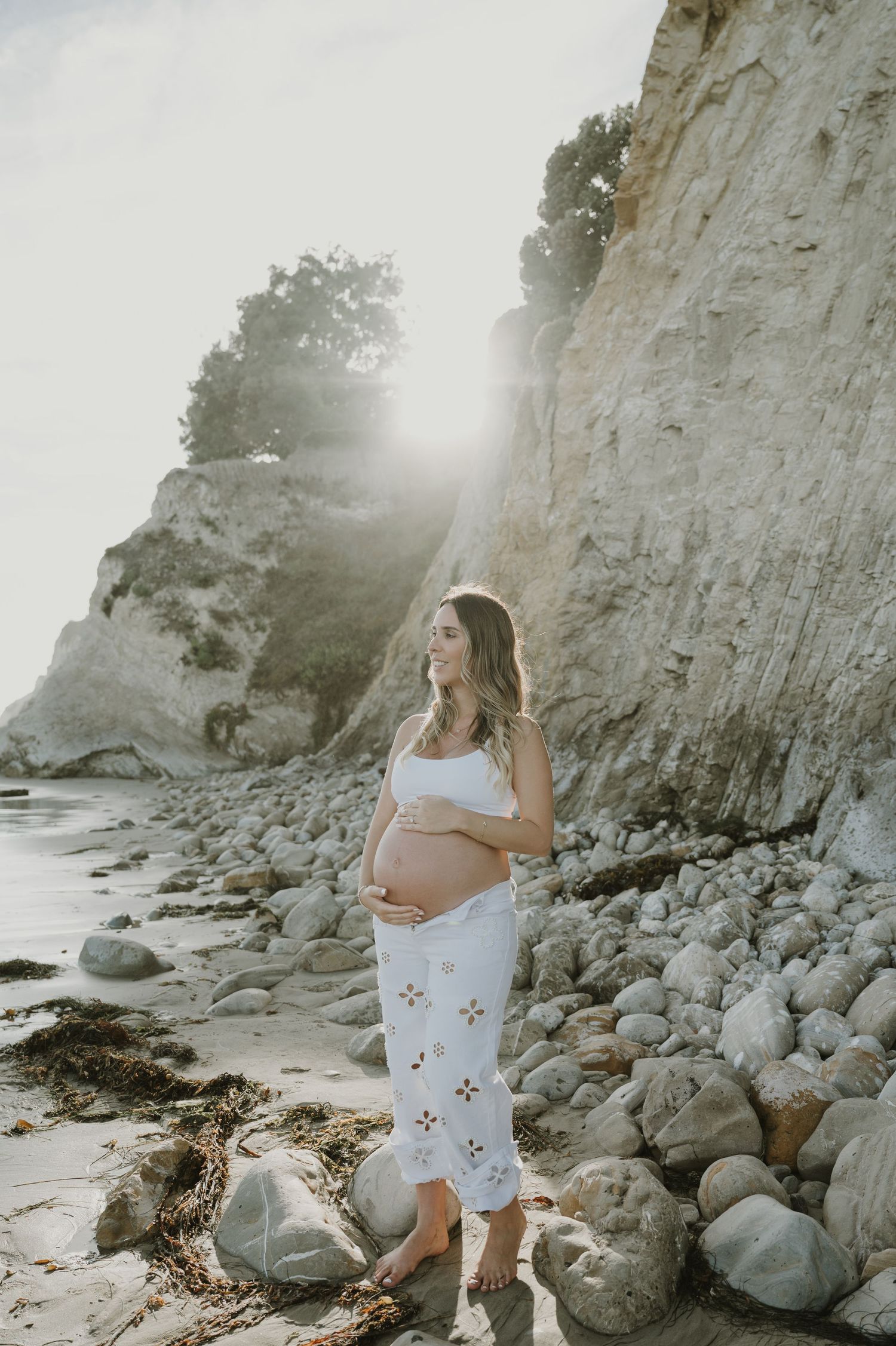A maternity photoshoot on a rocky beach with white cliffs in the background.
