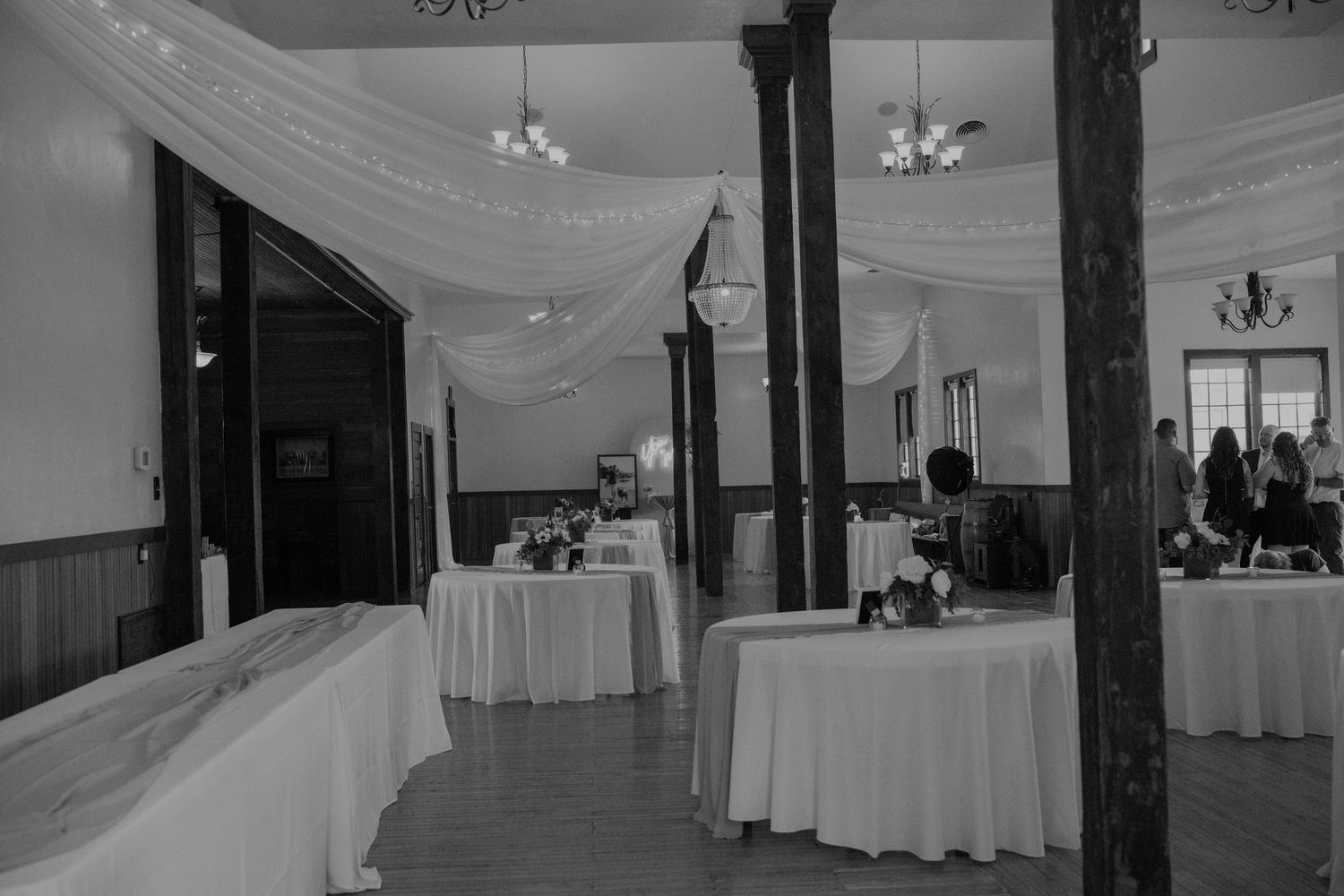 Modern banquet hall interior with white draped ceilings and round dining tables set for an event.