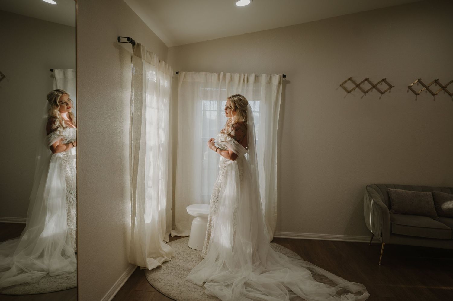 Dramatic wide shot of wedding dress silhouette in a minimalist room with natural light.