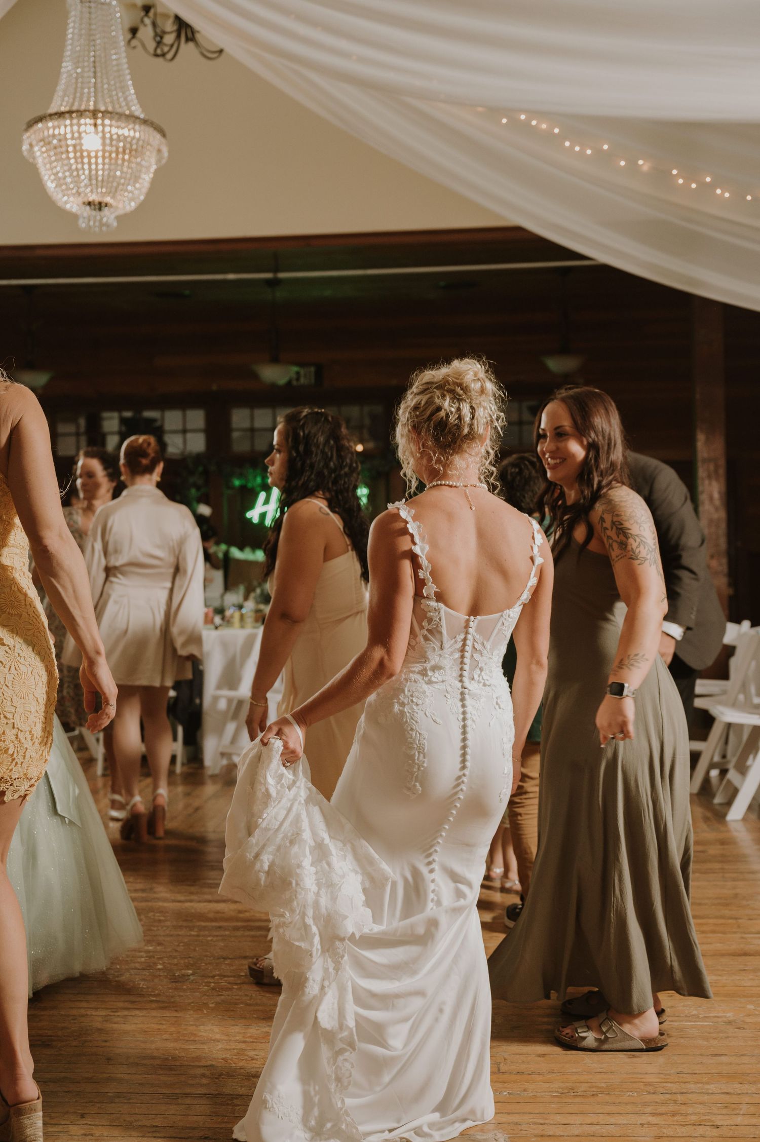 Wedding reception dance floor under crystal chandelier with white fabric draping.