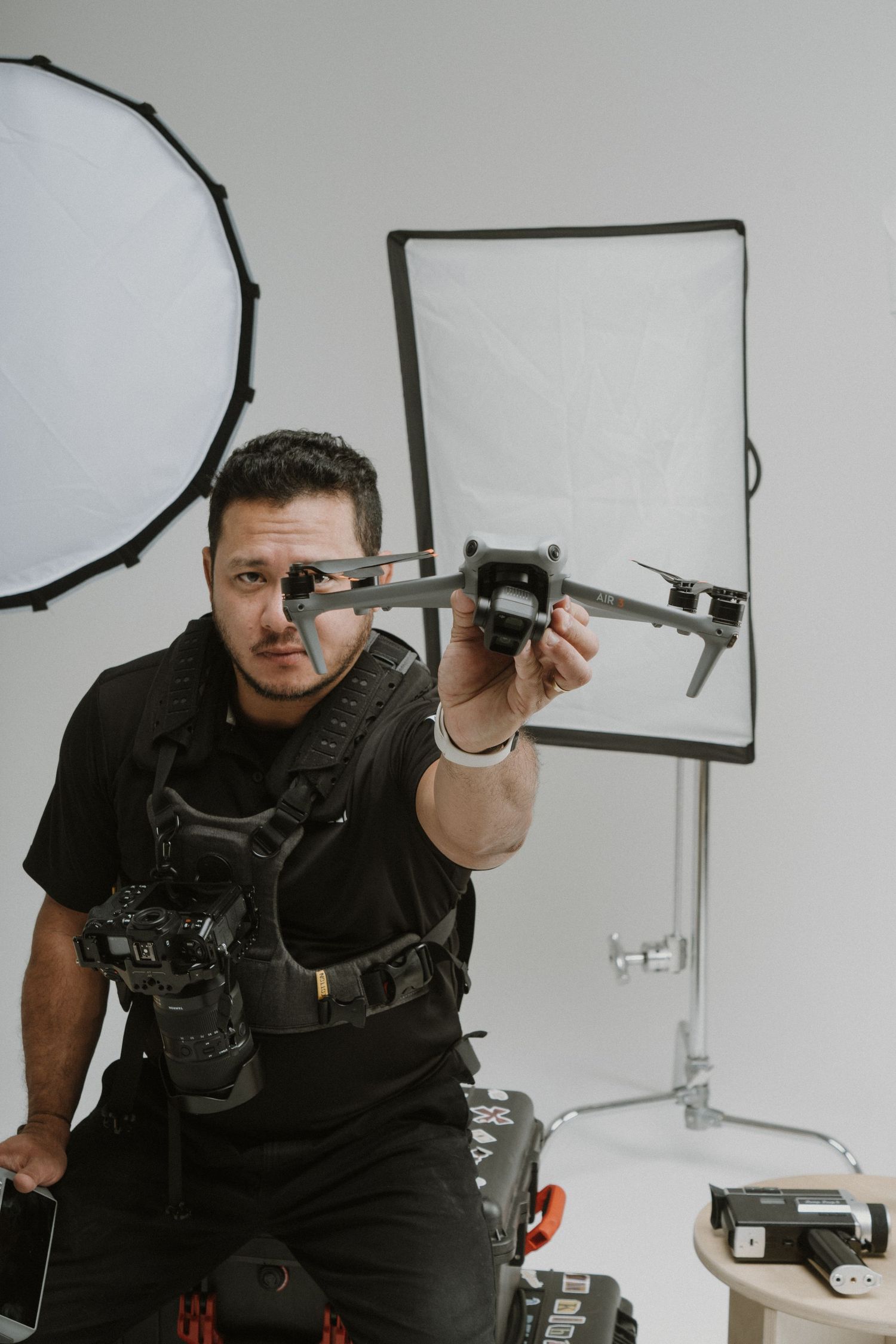 Photographer in black attire demonstrating drone equipment in studio.