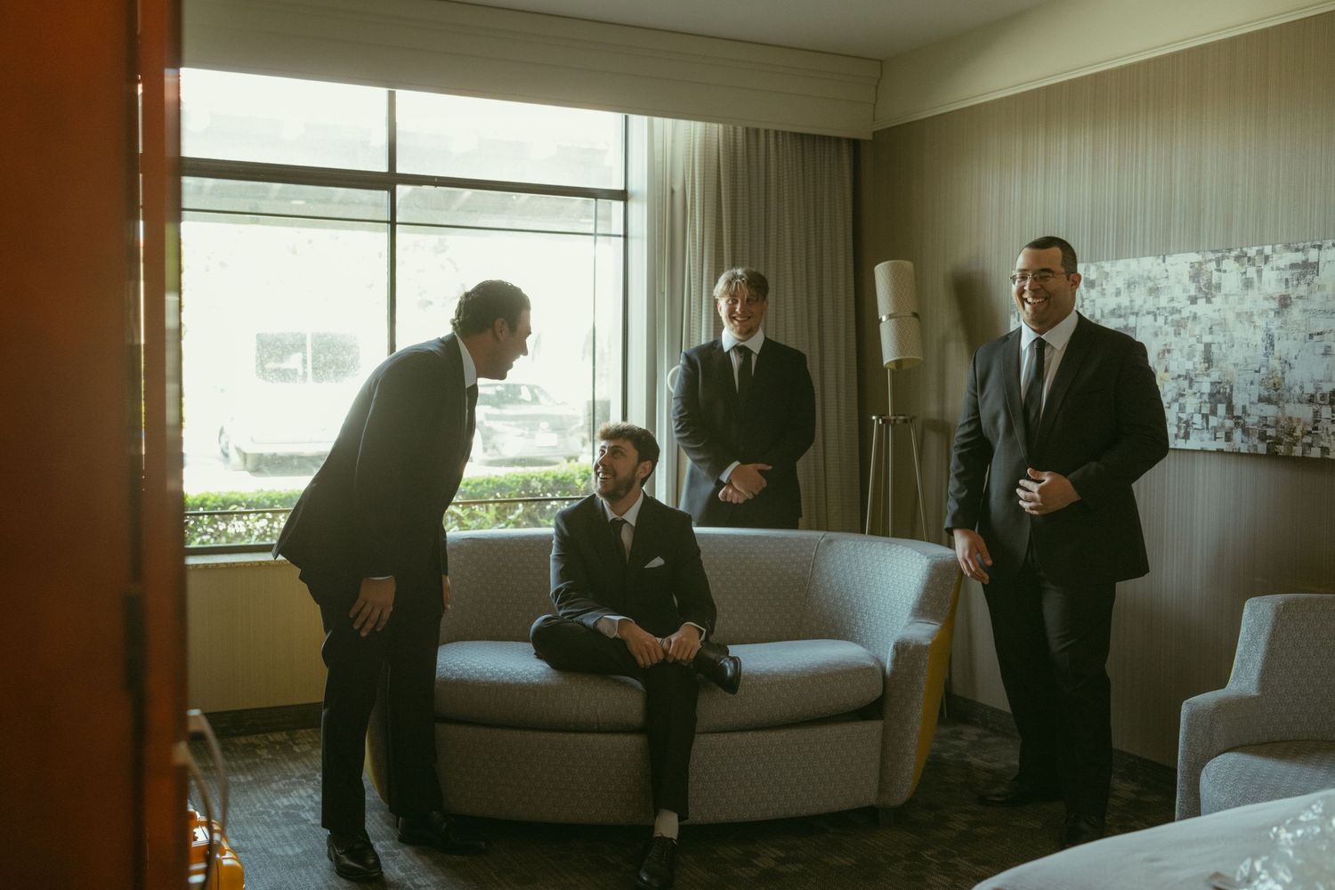 Groom and groomsmen gathered in hotel suite getting ready for wedding ceremony.