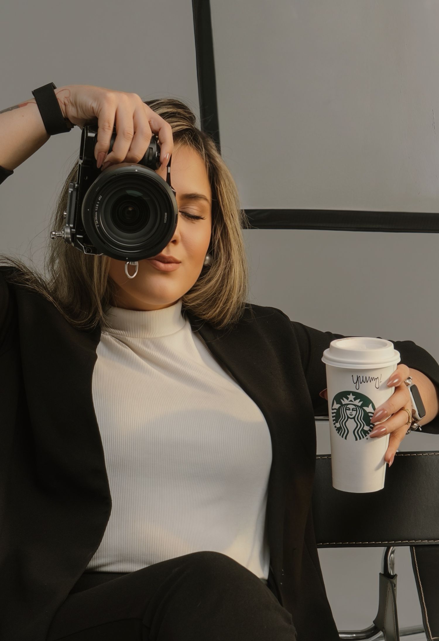 Photographer with camera and Starbucks cup in studio setting.