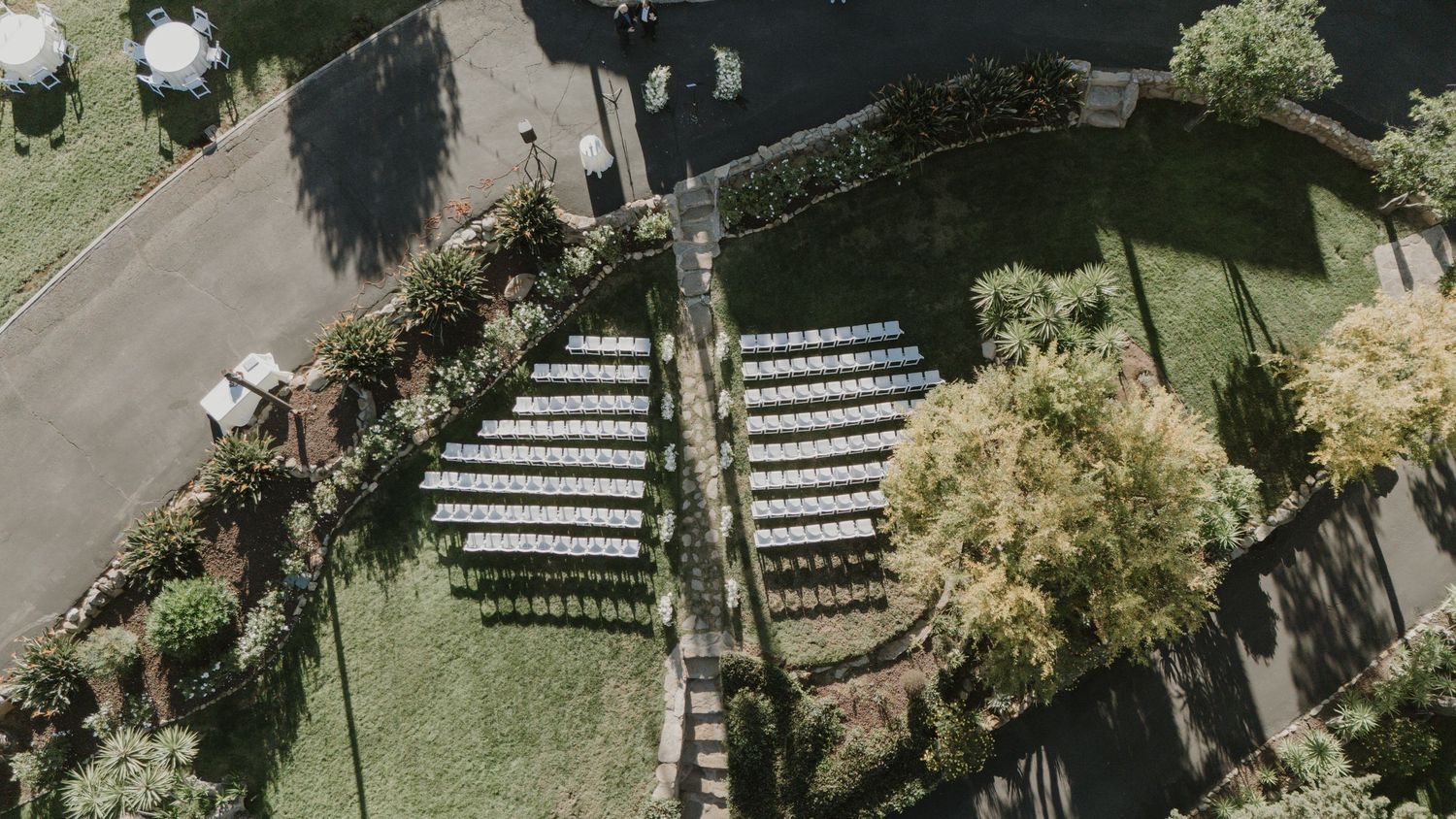 Aerial view of outdoor wedding ceremony setup with rows of white chairs.