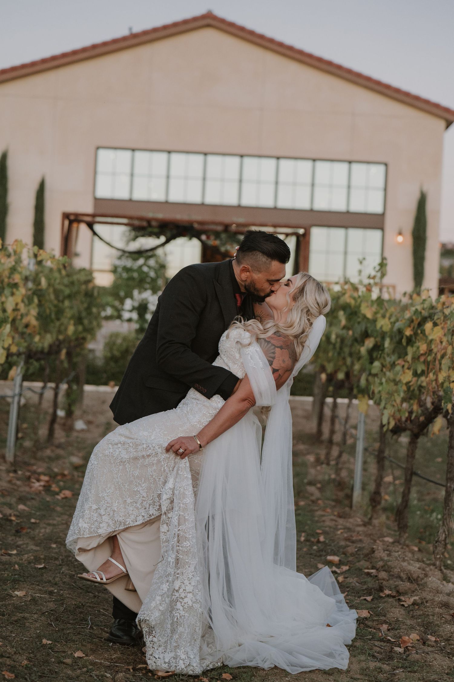 Romantic moment between newlyweds outside Mediterranean-style winery building.