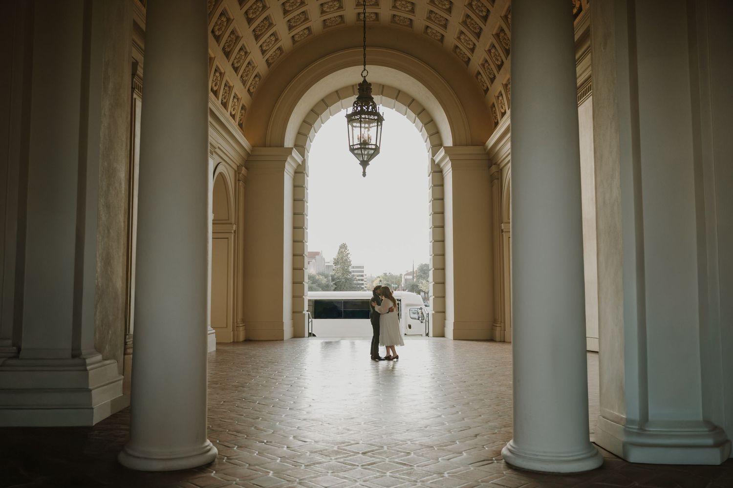 Long arched hallway with classical columns creating dramatic lighting and shadows.