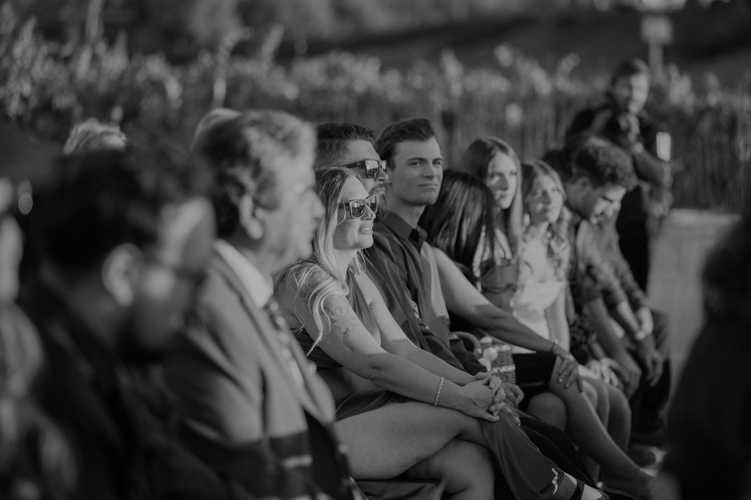Black and white photo of wedding guests seated during an outdoor celebration.