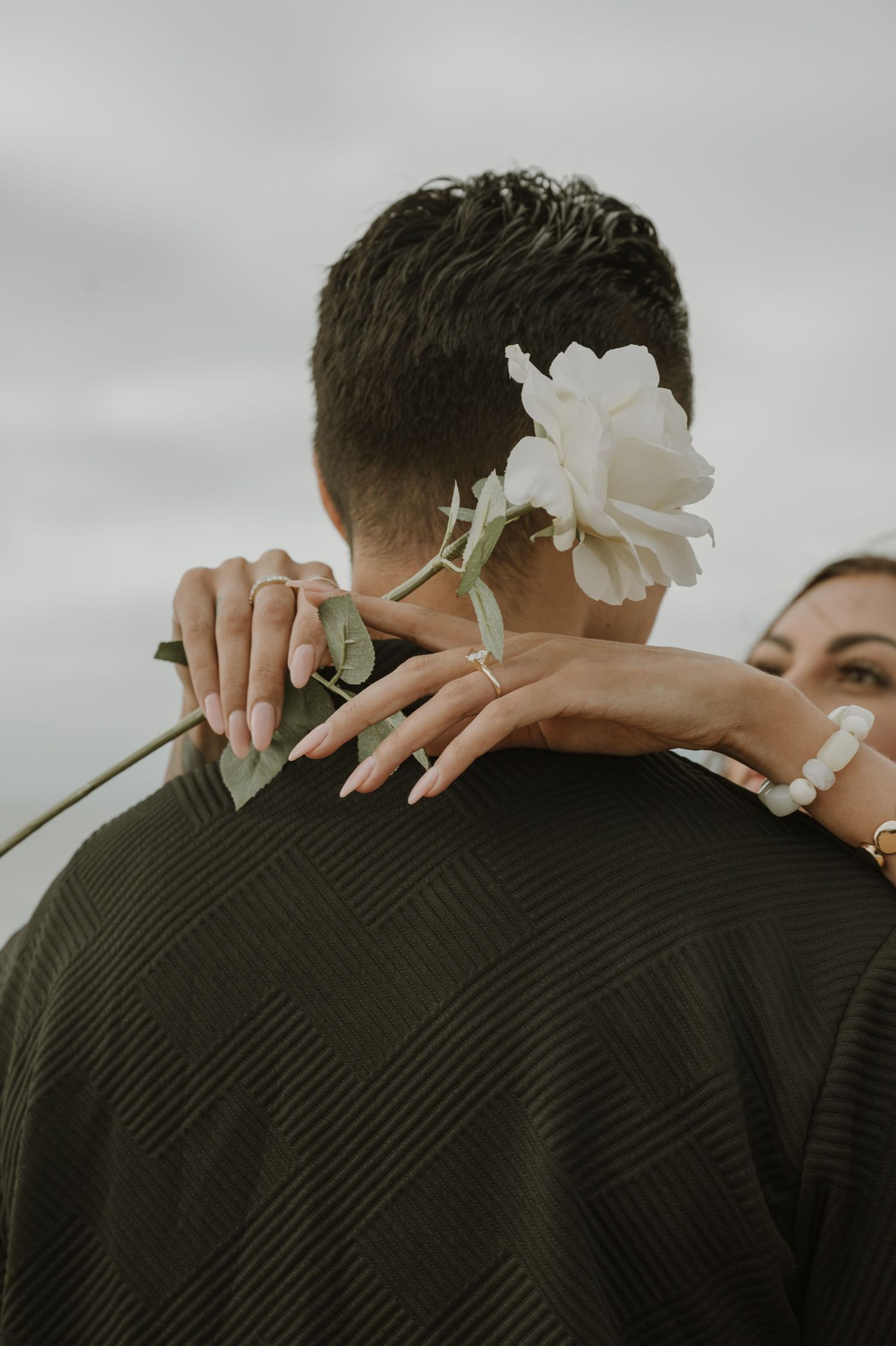 Intimate close-up showing gentle embrace with white flower detail.