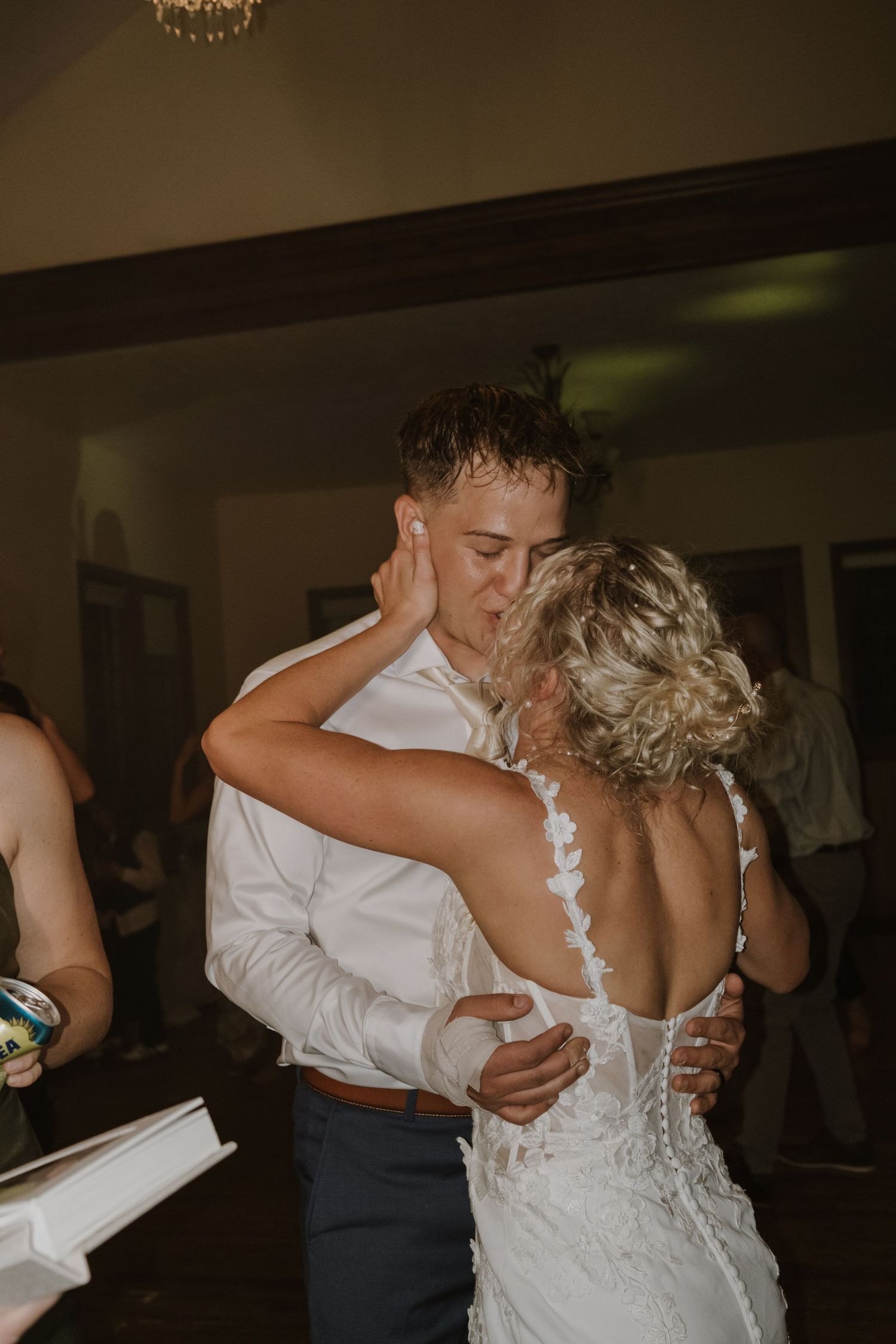 A couple shares a romantic slow dance at their wedding reception in a dimly lit venue.