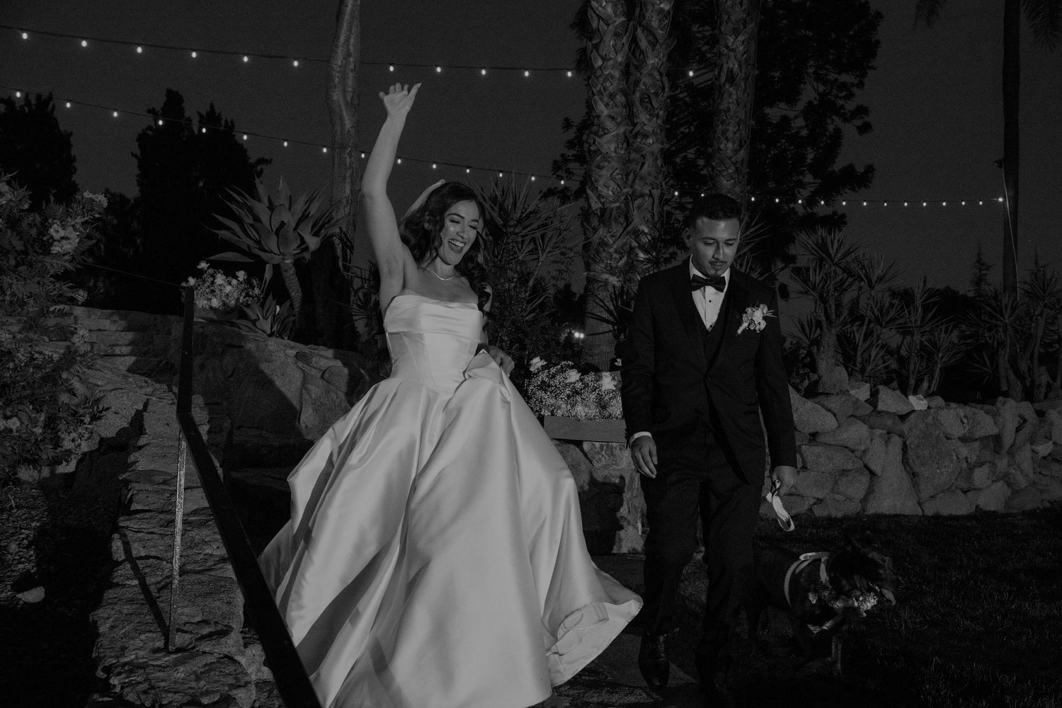 Guests dancing in a dimly lit reception hall with string lights overhead.