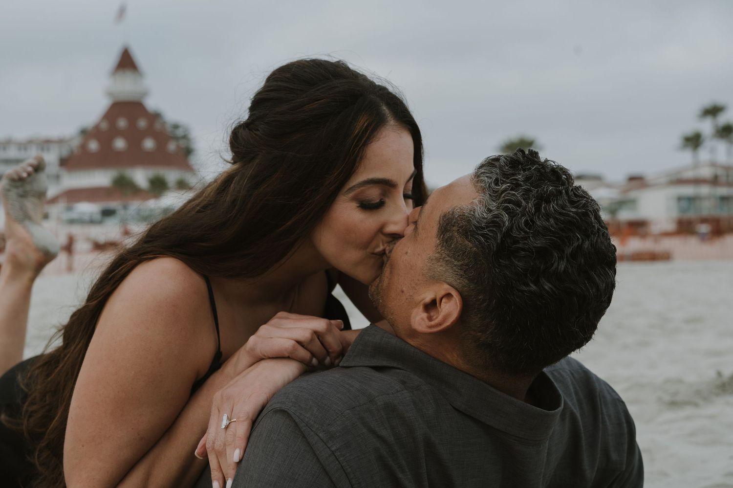 Intimate beach photoshoot with couple against ocean backdrop.