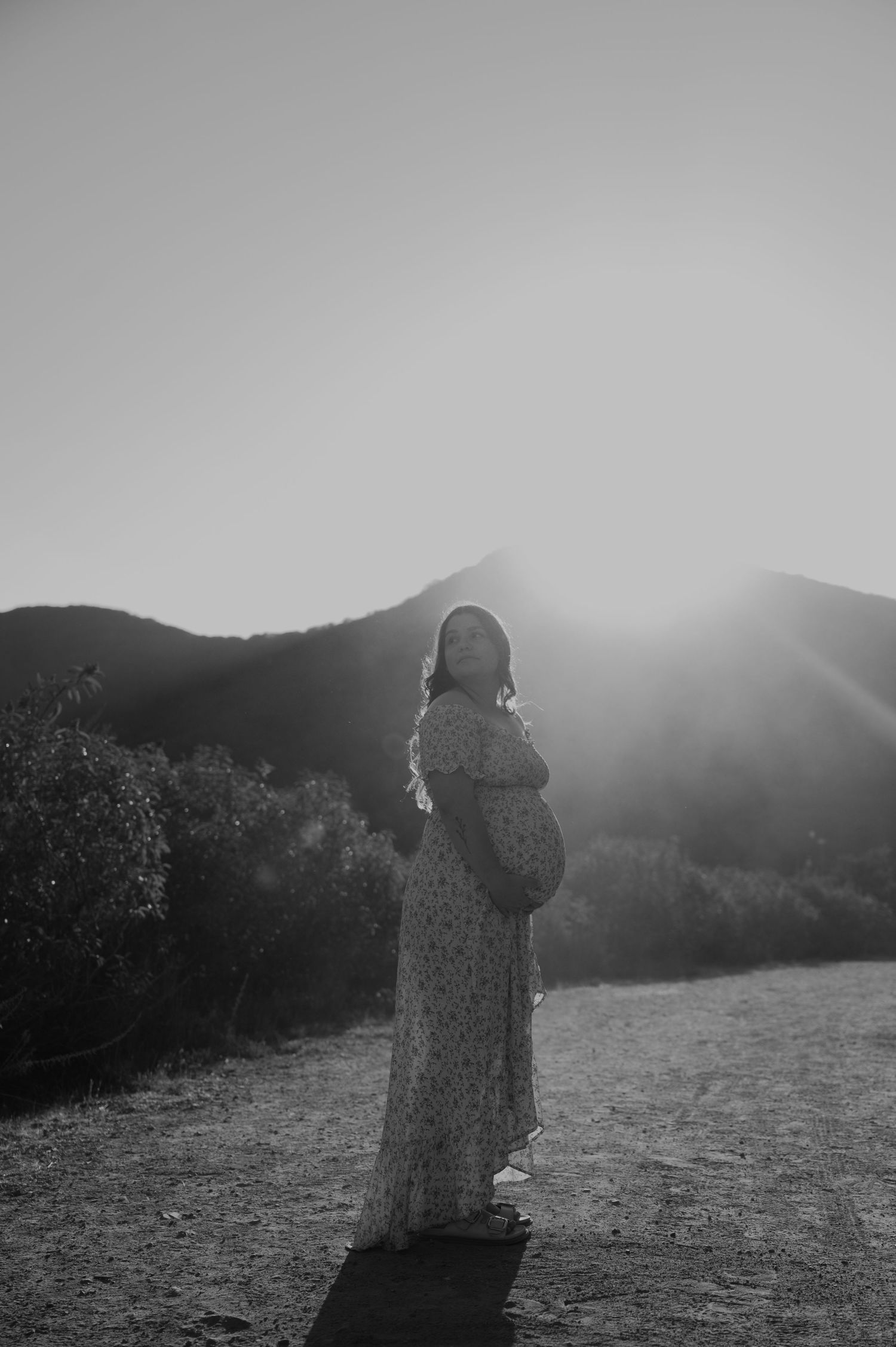 Black and white photo of two people sharing an intimate moment on a mountain path.
