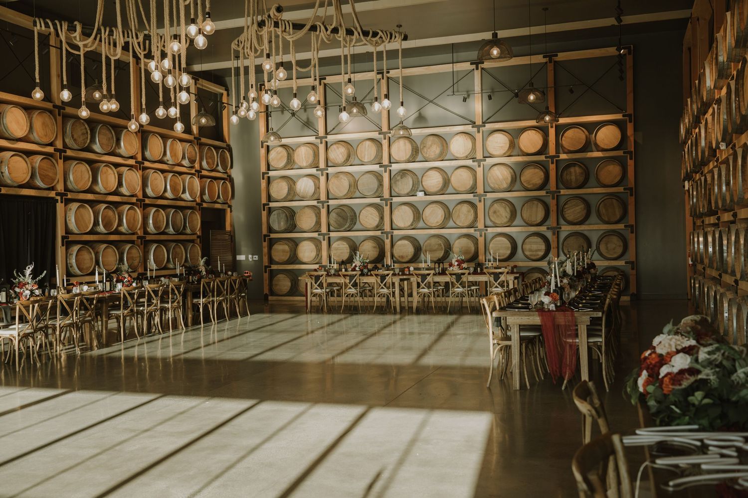 Elegant rustic wedding venue interior with wooden barrels and romantic lighting creating a warm ambiance.