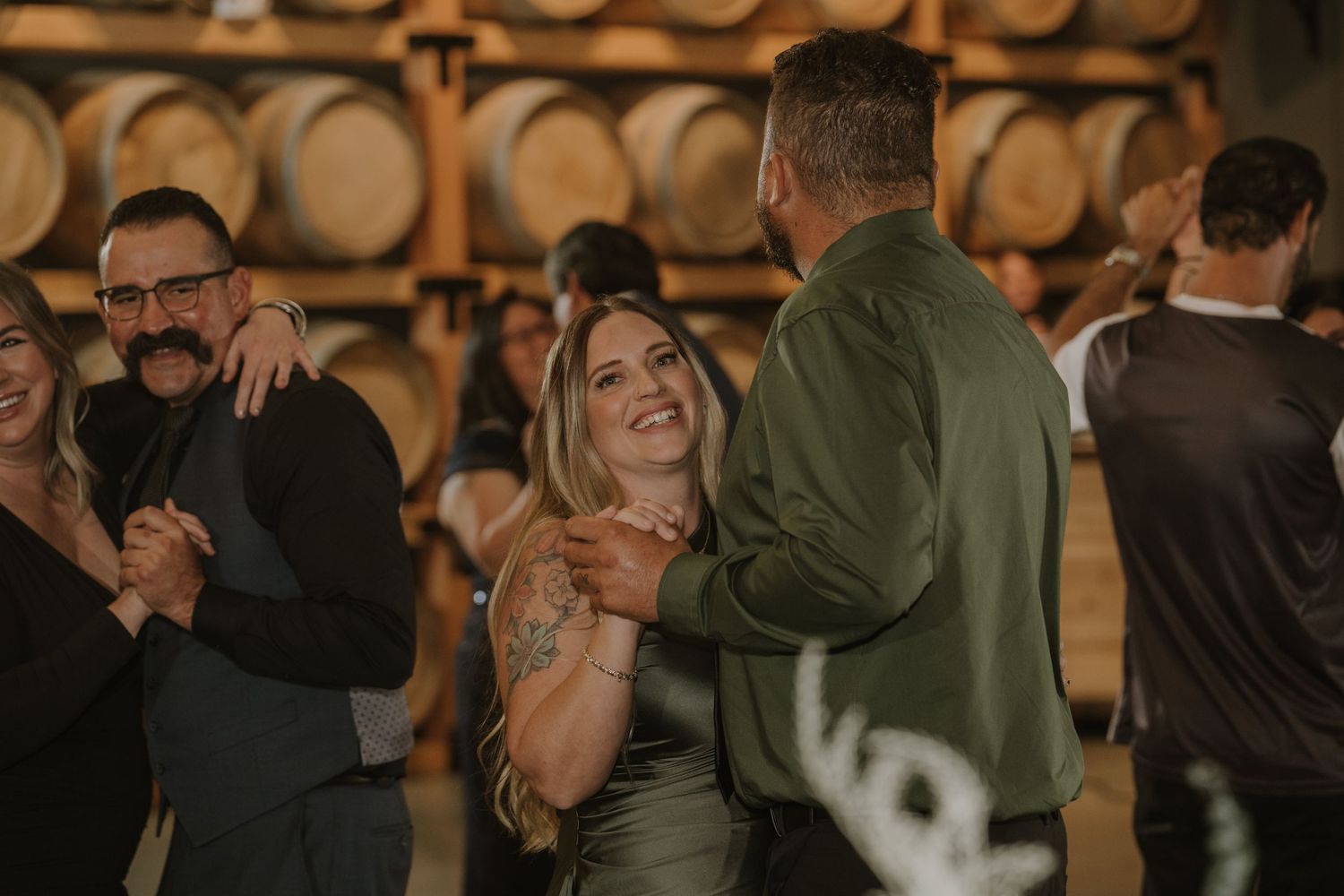 Celebration in a rustic winery barrel room with warm ambient lighting.