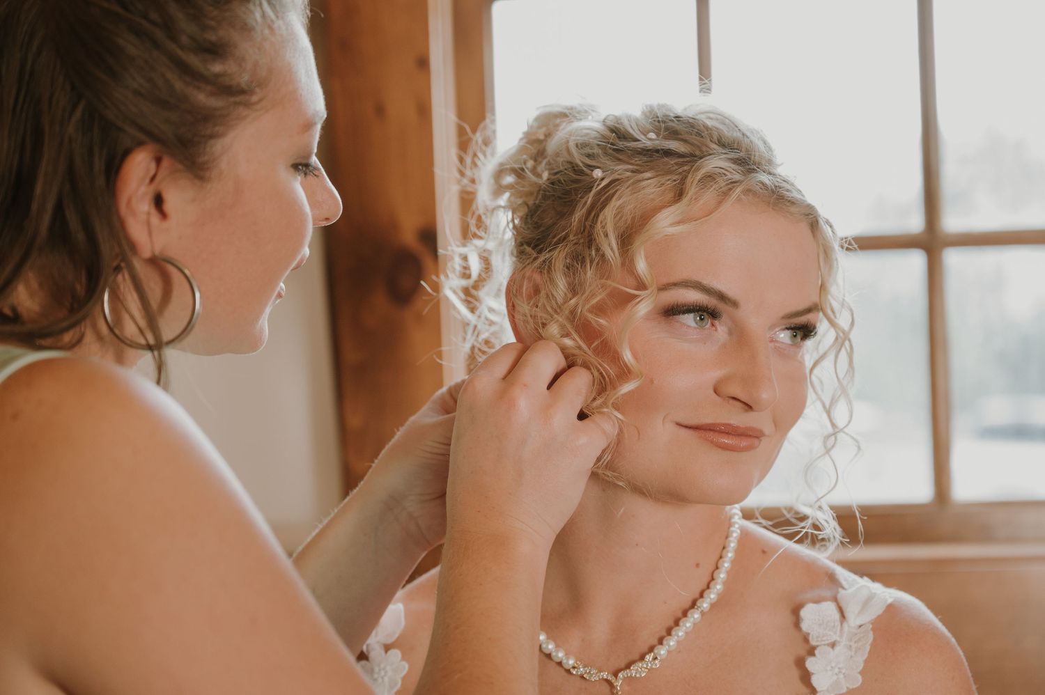 Warm-toned candid wedding preparation moments captured by window light.