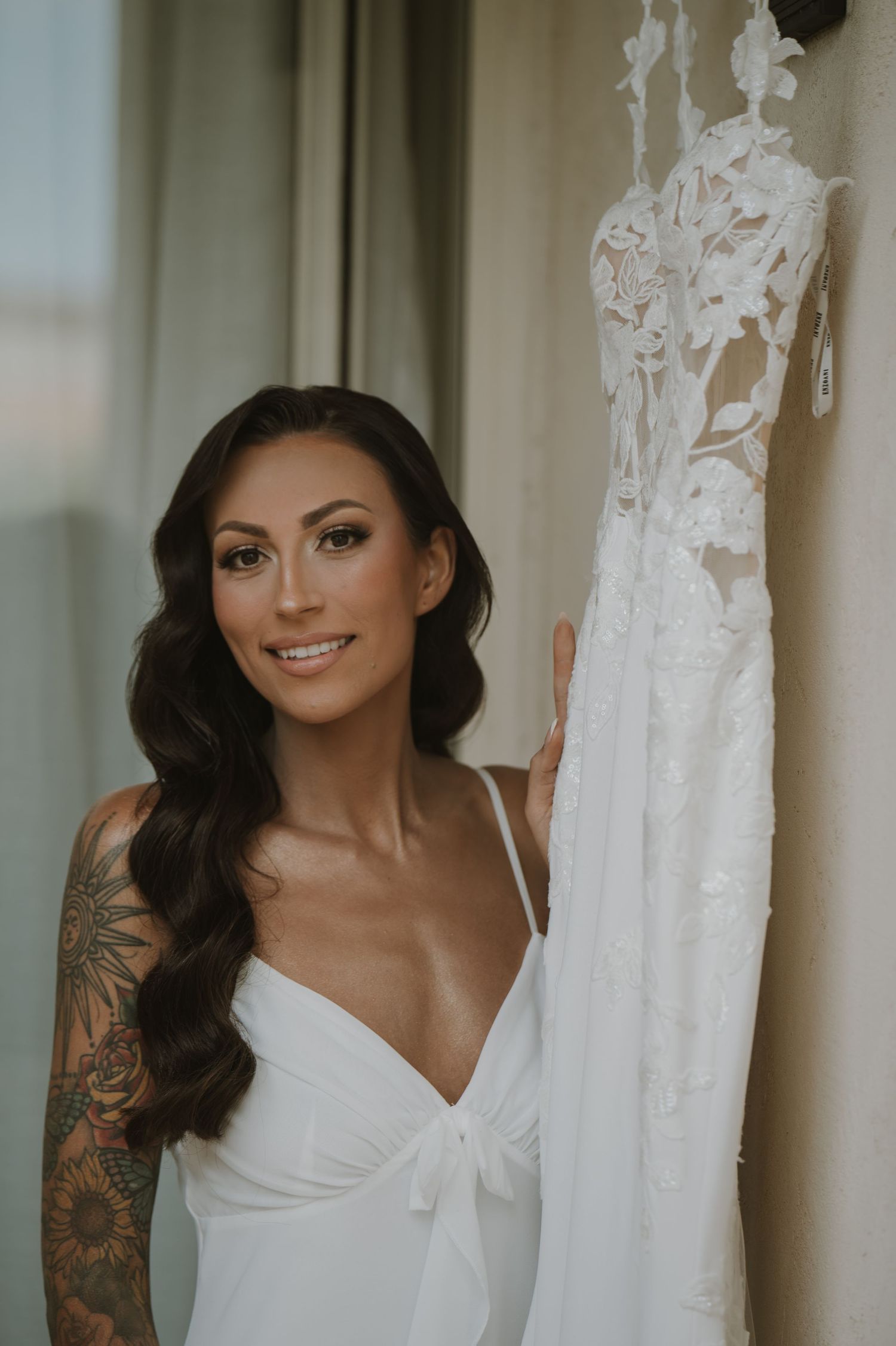 Wedding dress detail shot showing intricate lace and floral embellishments against a light background.