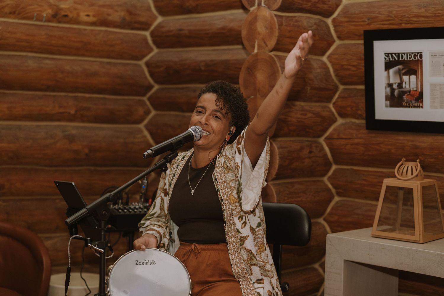 Singer performing at microphone with arm raised in log cabin venue.