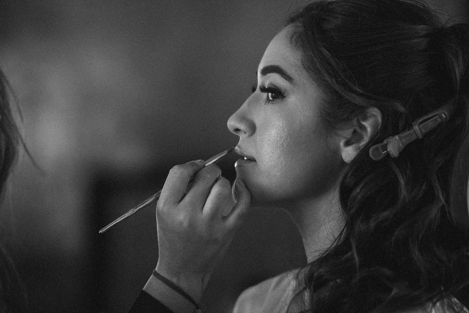 Artistic black and white profile shot showing wedding day makeup preparation.