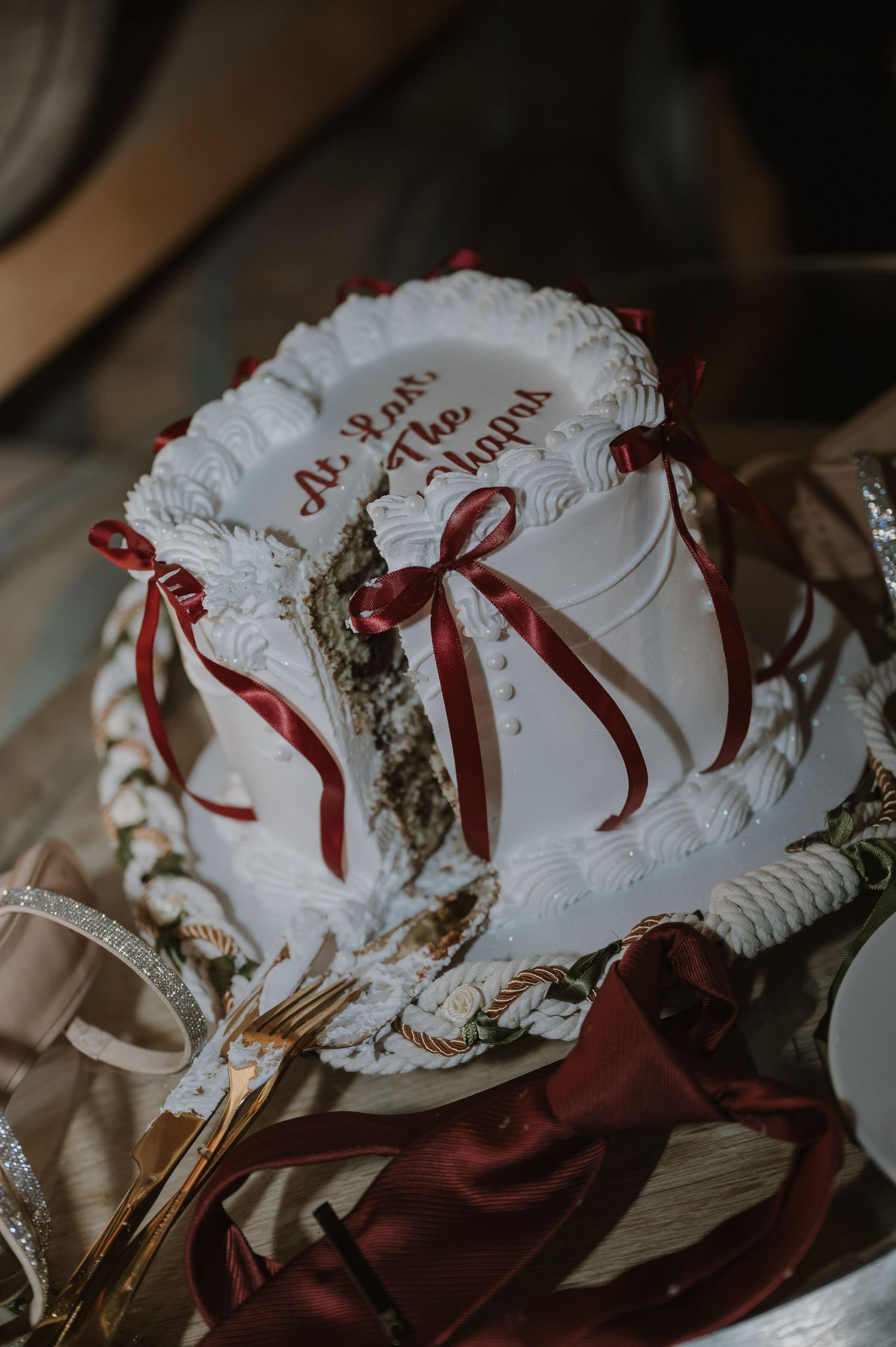 White vintage bonnet with red ribbons displayed against dark background.