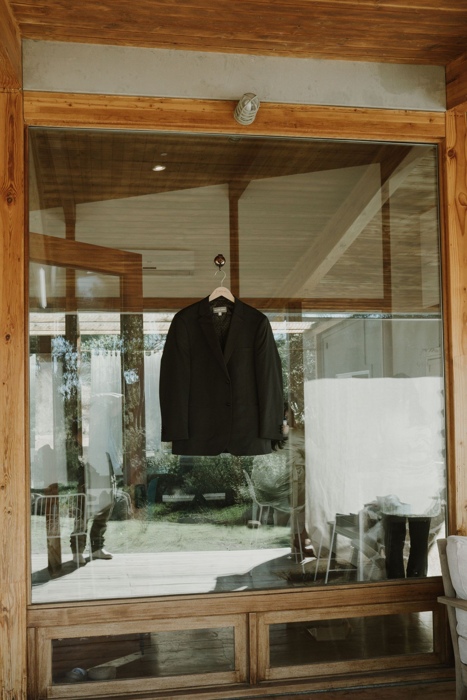 Black garments hang in a rustic wooden display case with glass windows.