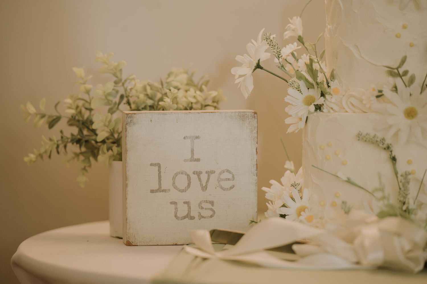 Rustic wooden signs with romantic text displayed among white floral arrangements.