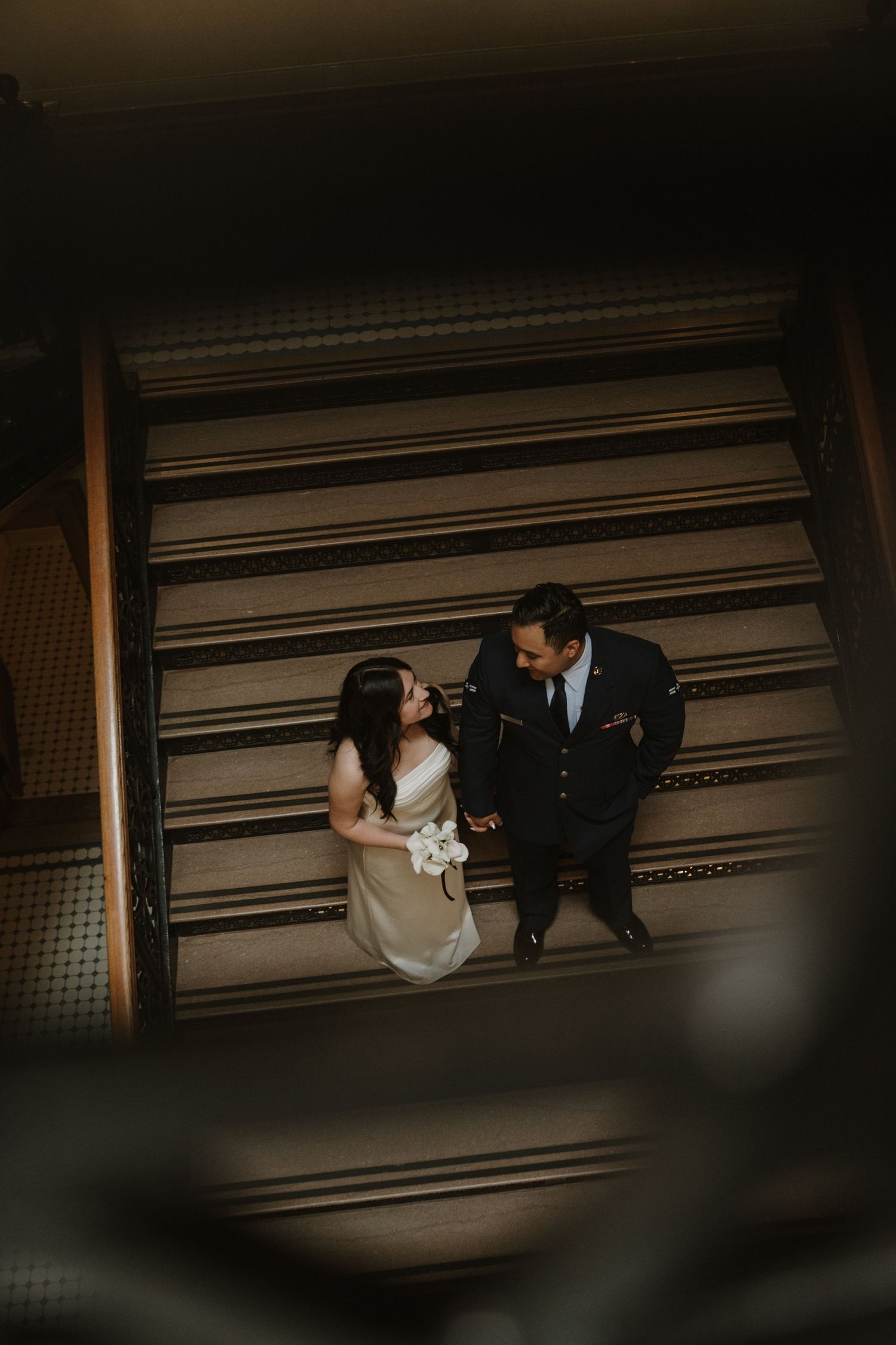 An overhead view of a couple in formal attire on vintage wooden floors.
